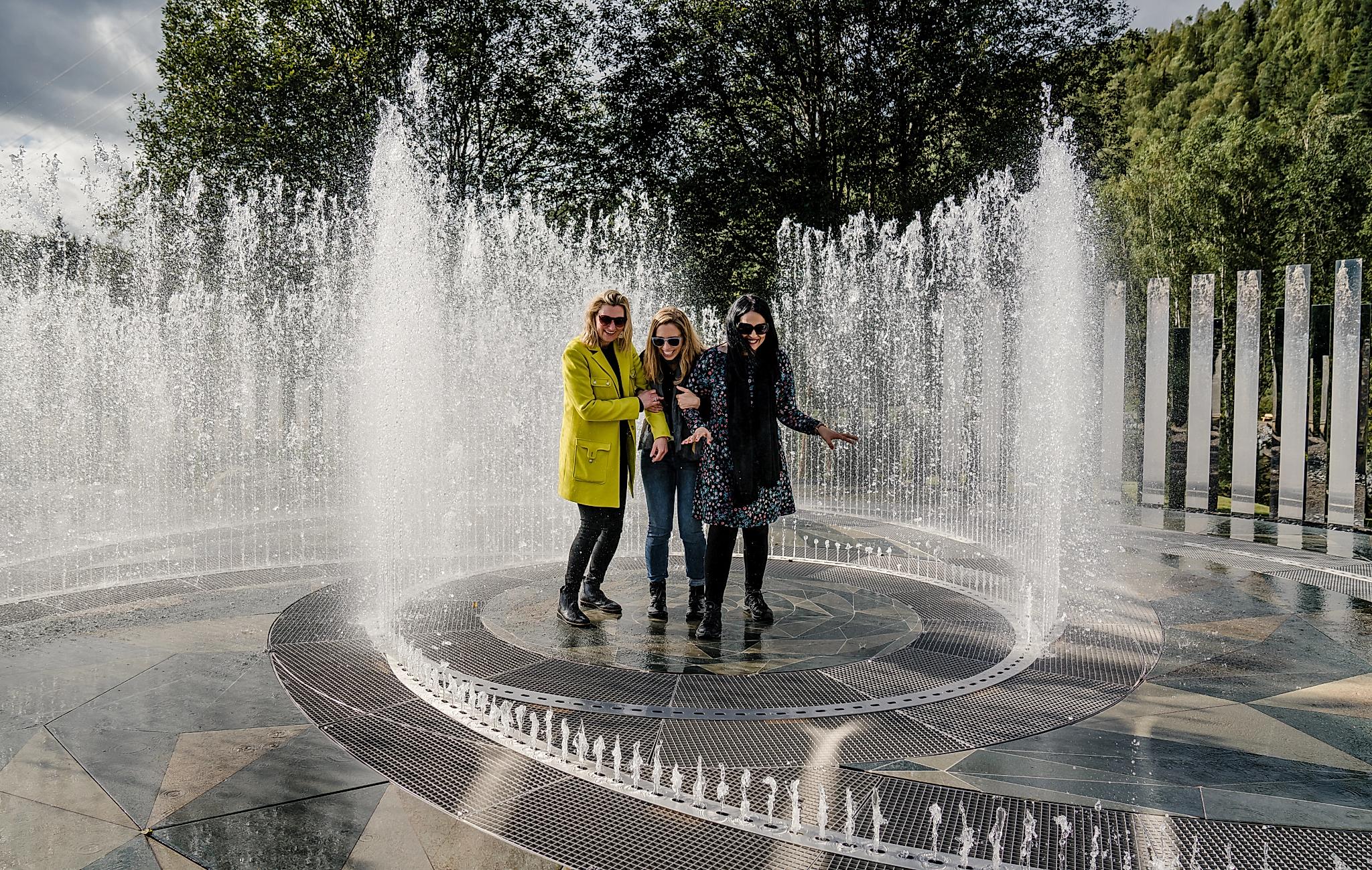 Four laughing women standing in the fountain surrounded by mirrors at Kistefos Museum in Hadeland