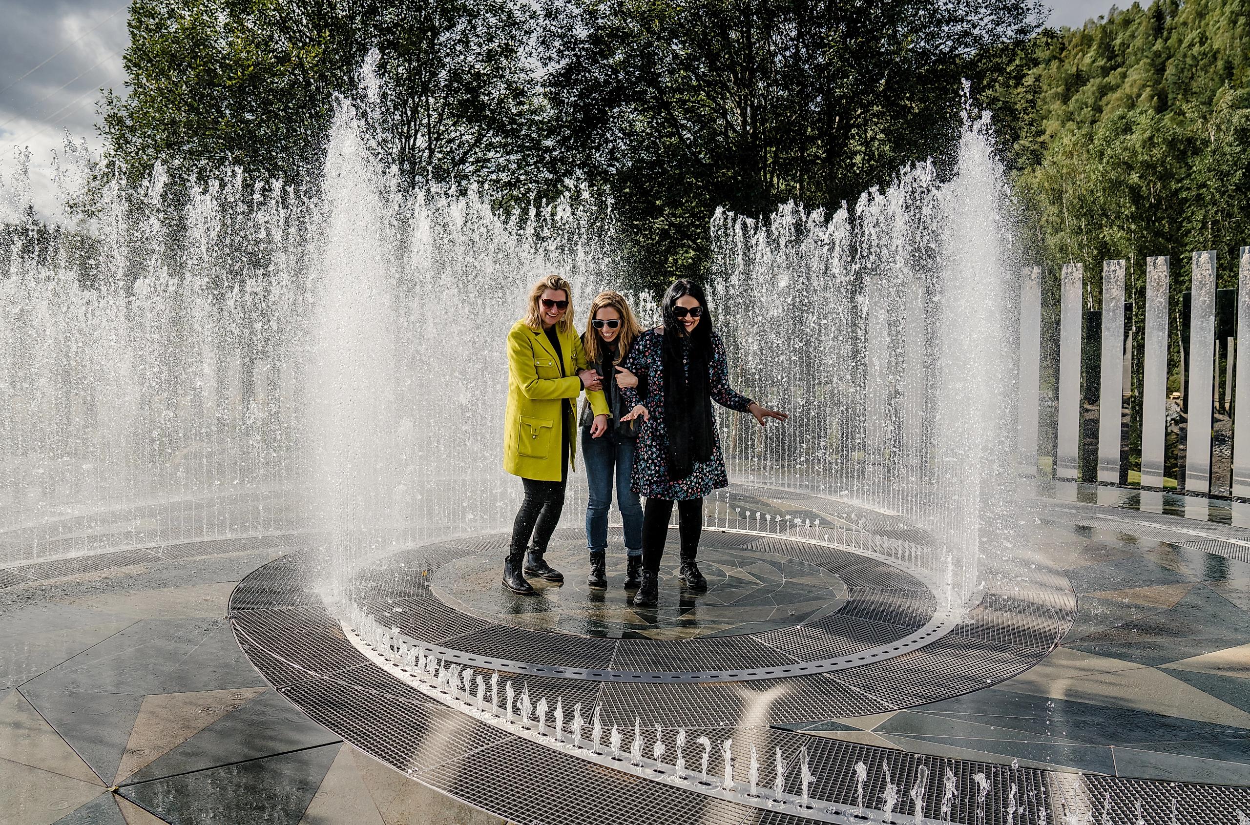 Four laughing women standing in the fountain surrounded by mirrors at Kistefos Museum in Hadeland