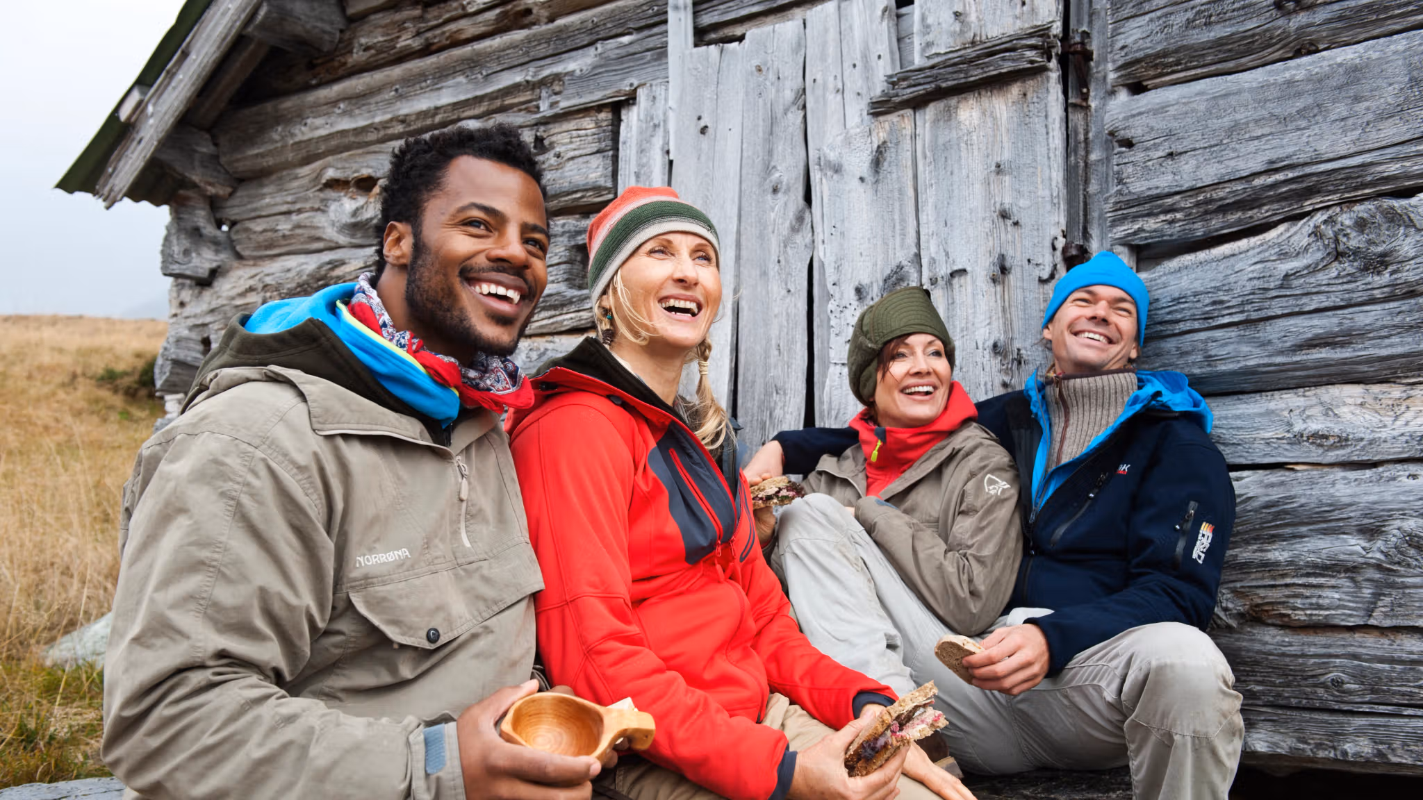 Four happy people sitting outside of a mountain cabin in Beitostølen, Eastern Norway