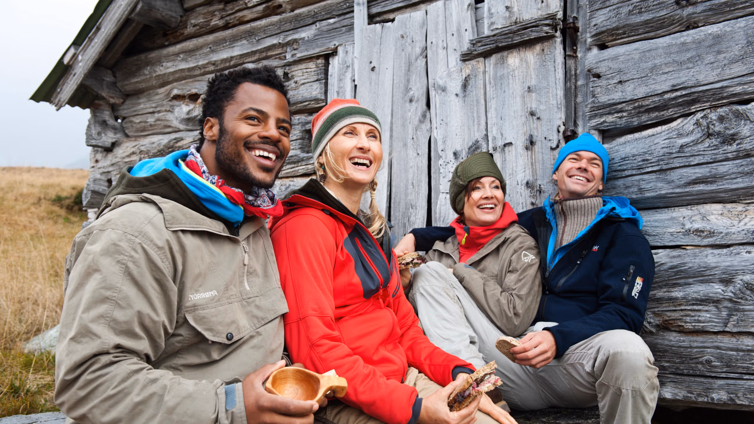 Four happy people sitting outside of a mountain cabin in Beitostølen, Eastern Norway