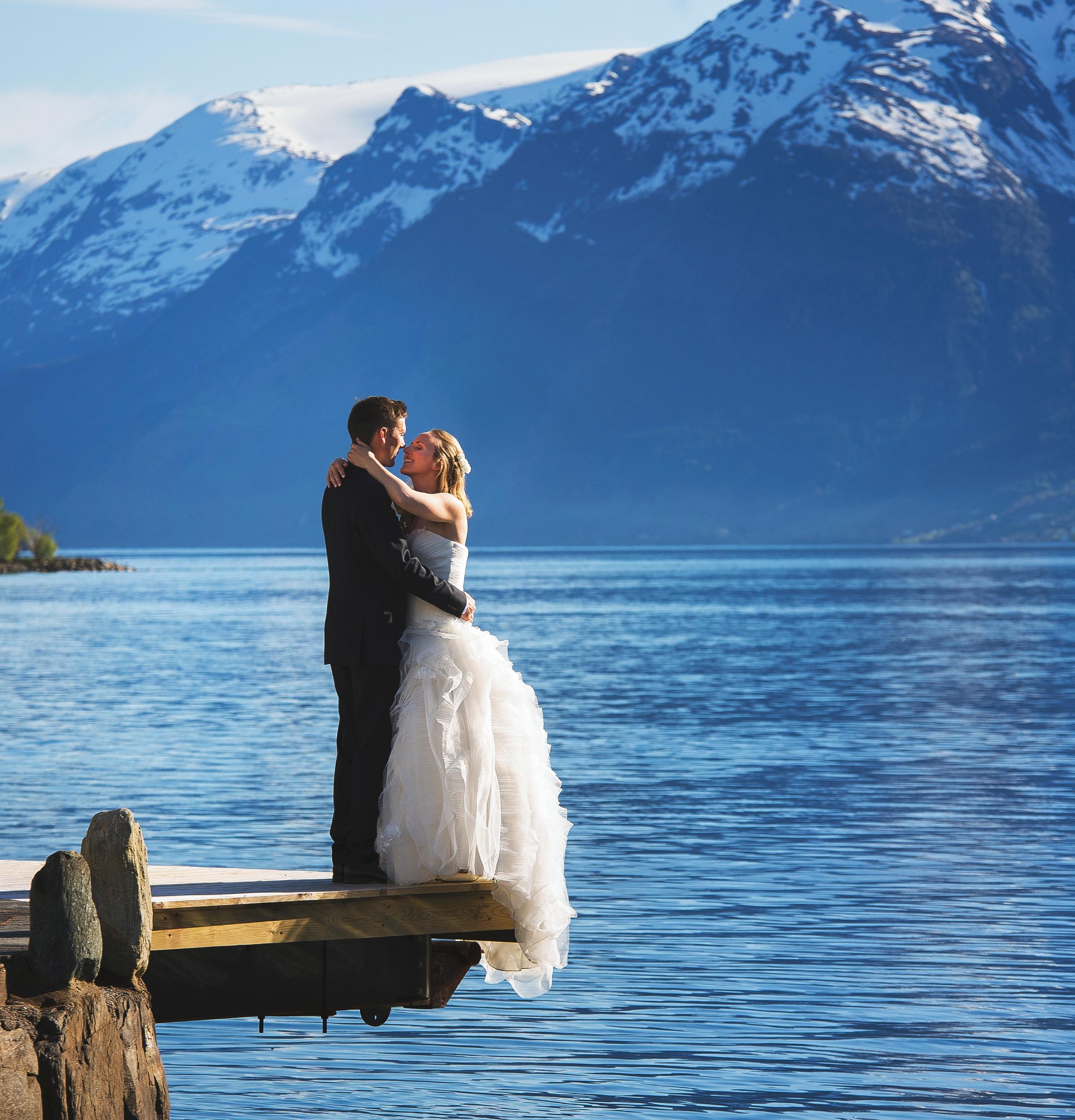 A bride and groom out by the fjord with mountains in the background in Ullensvang in Fjord Norway