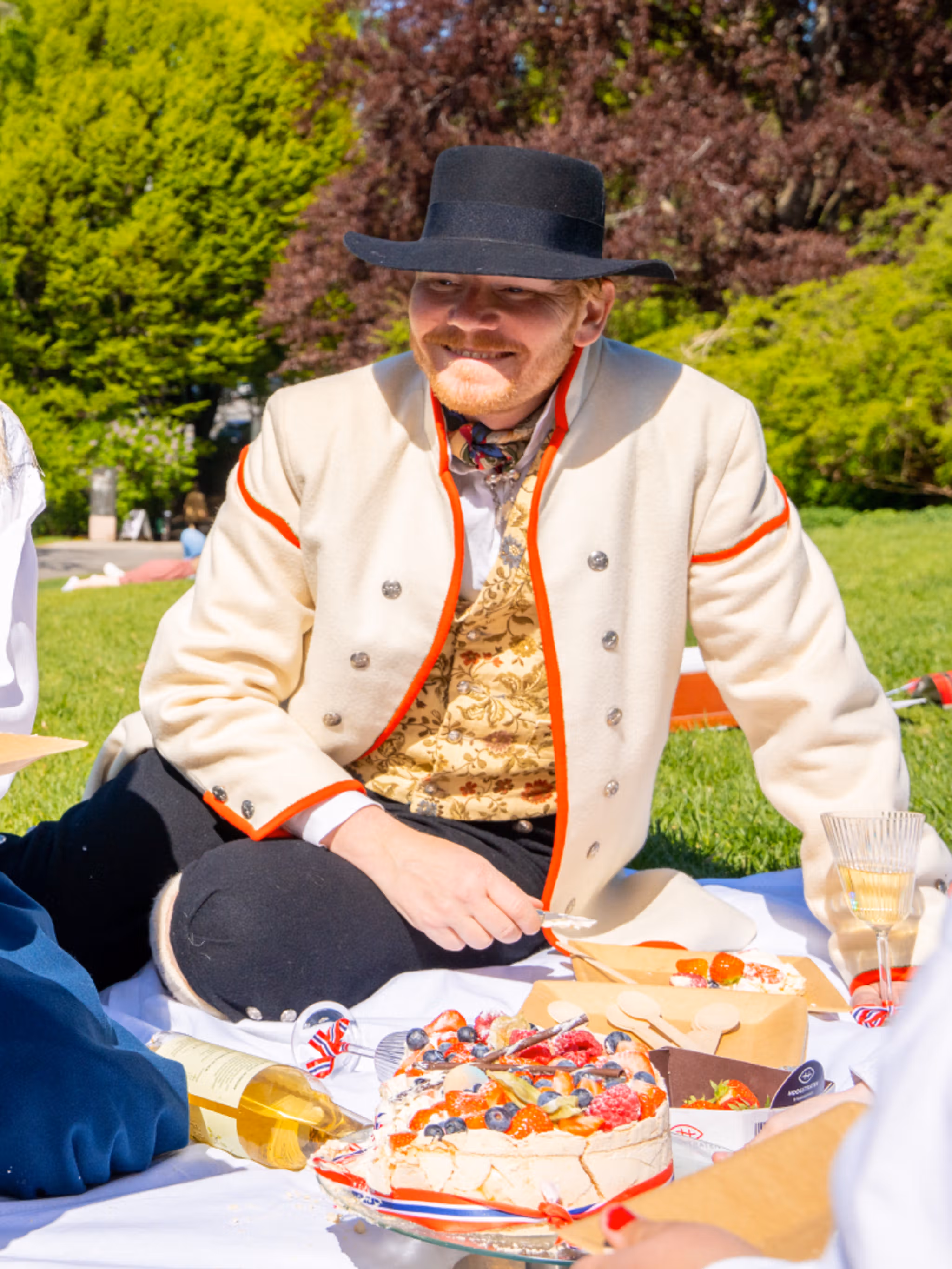 People enjoying festive food in the park wearing bunads on 17 of May - Norway’s national day