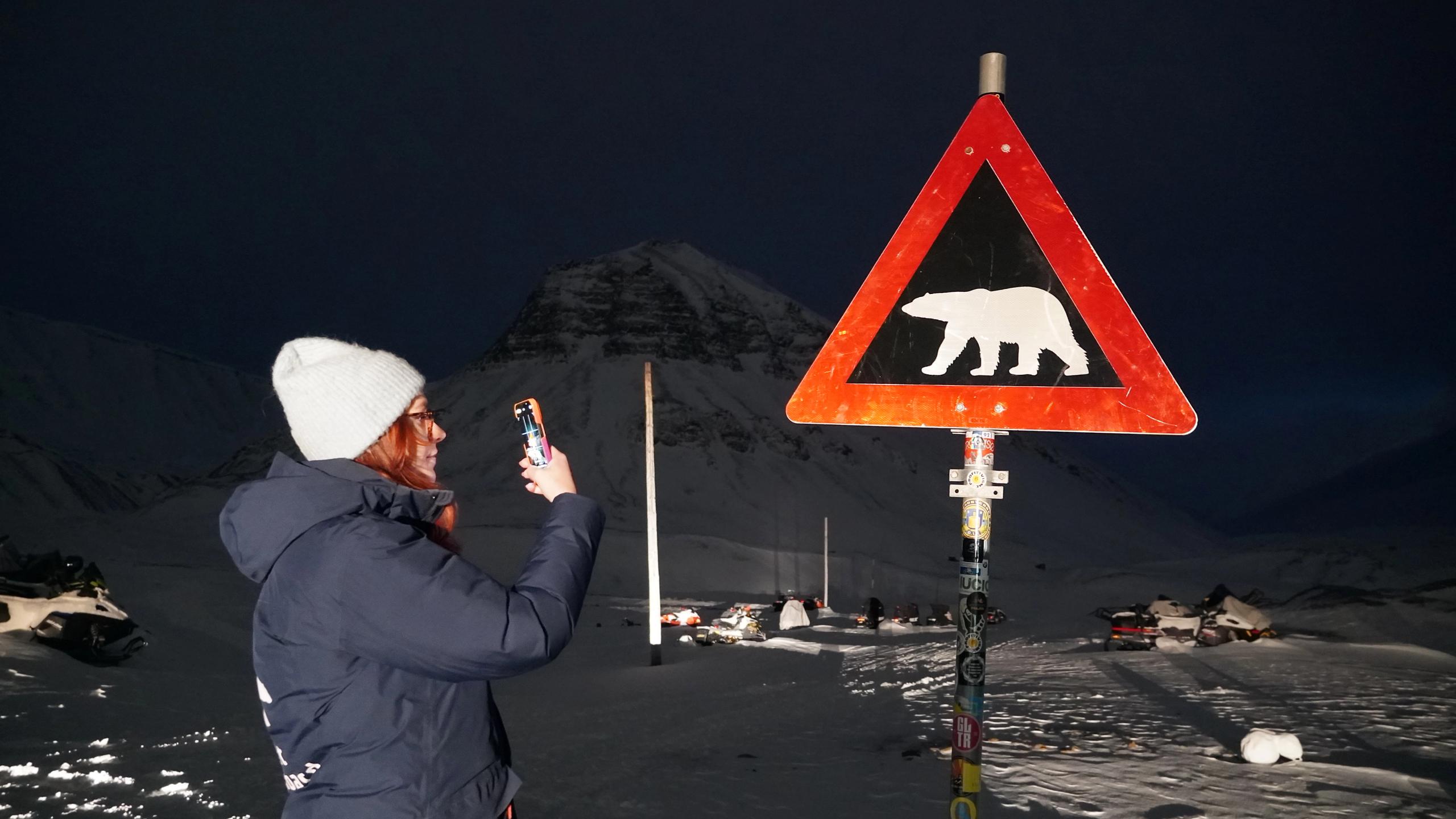Woman in front of a polar bear sign in Svalbard