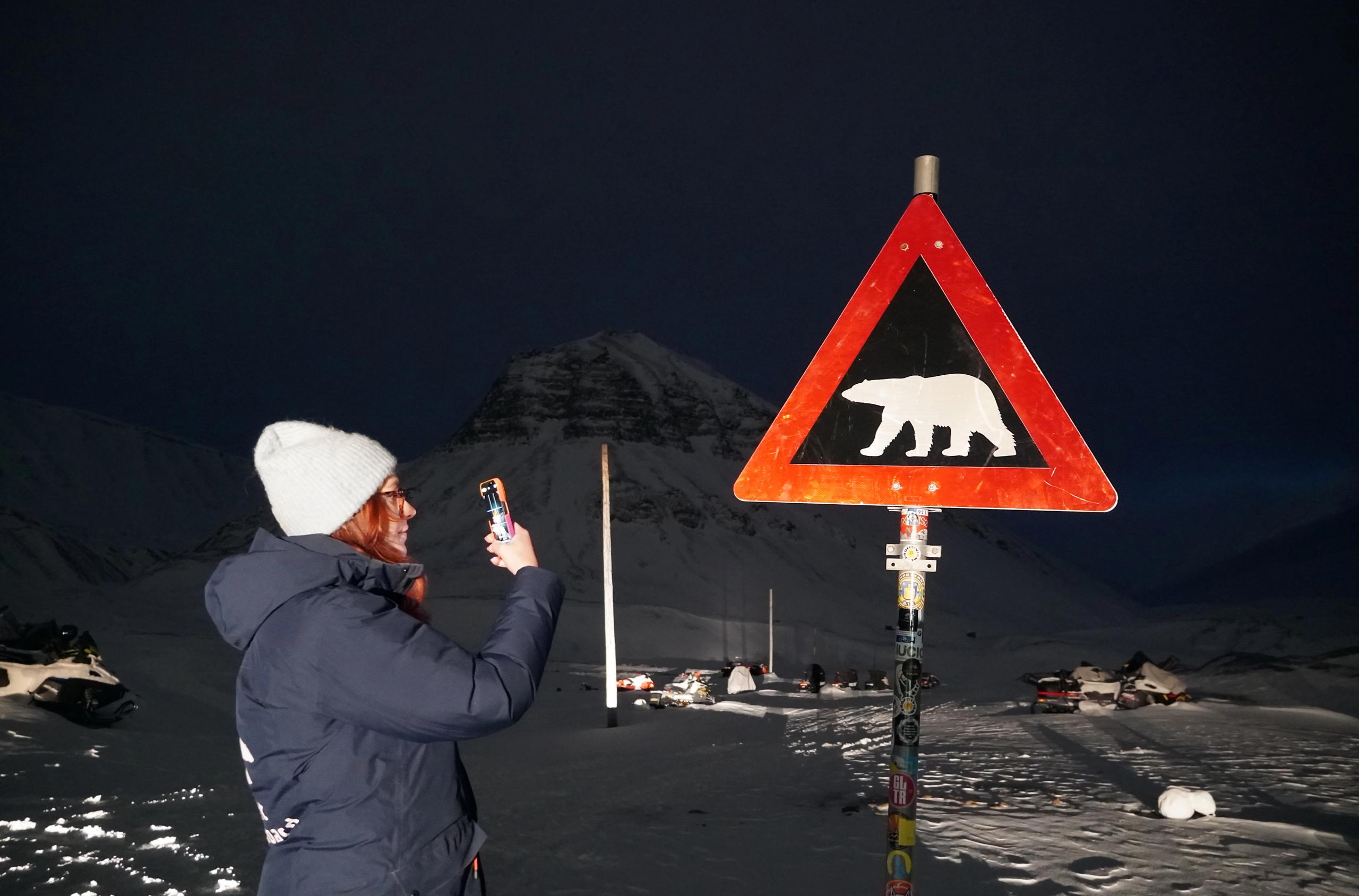 Dame foran isbjørnskilt på Svalbard