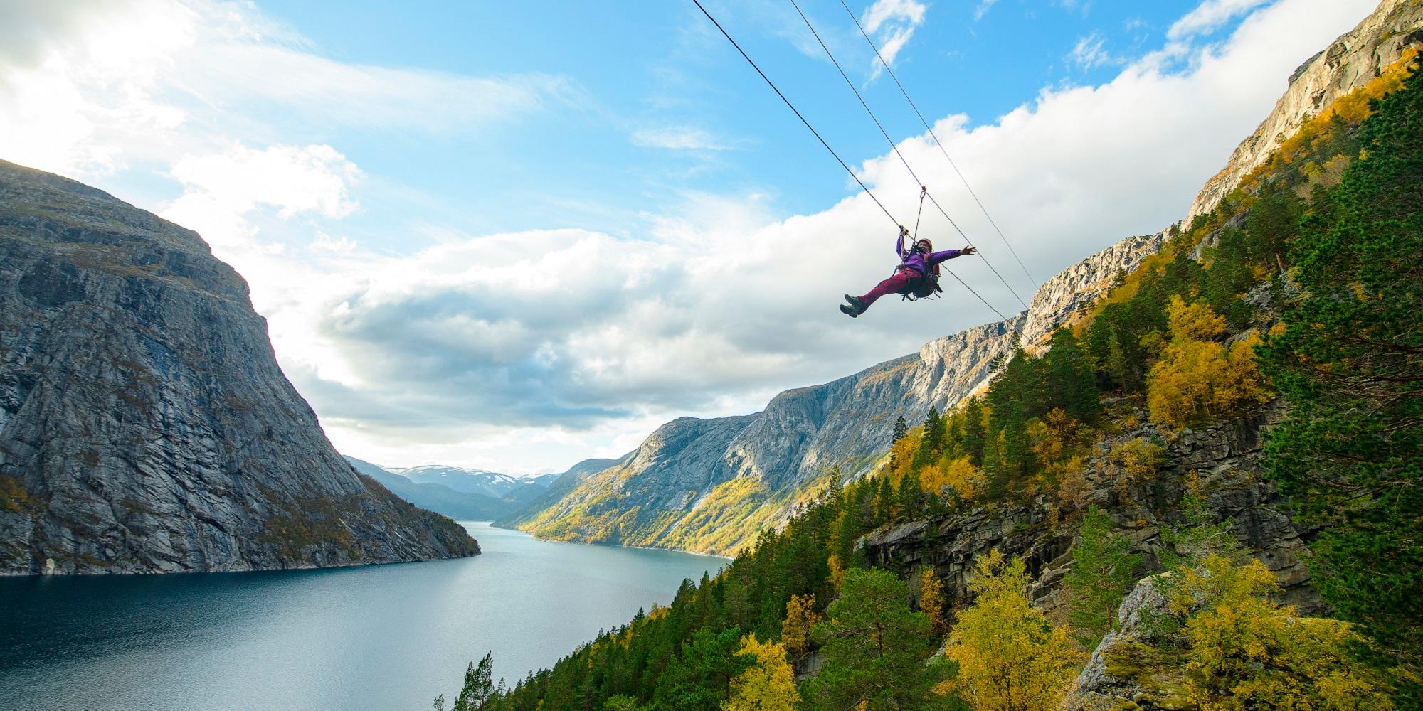 En kvinna som glider ner för en zipline i närheten av Trolltunga i Fjord Norge
