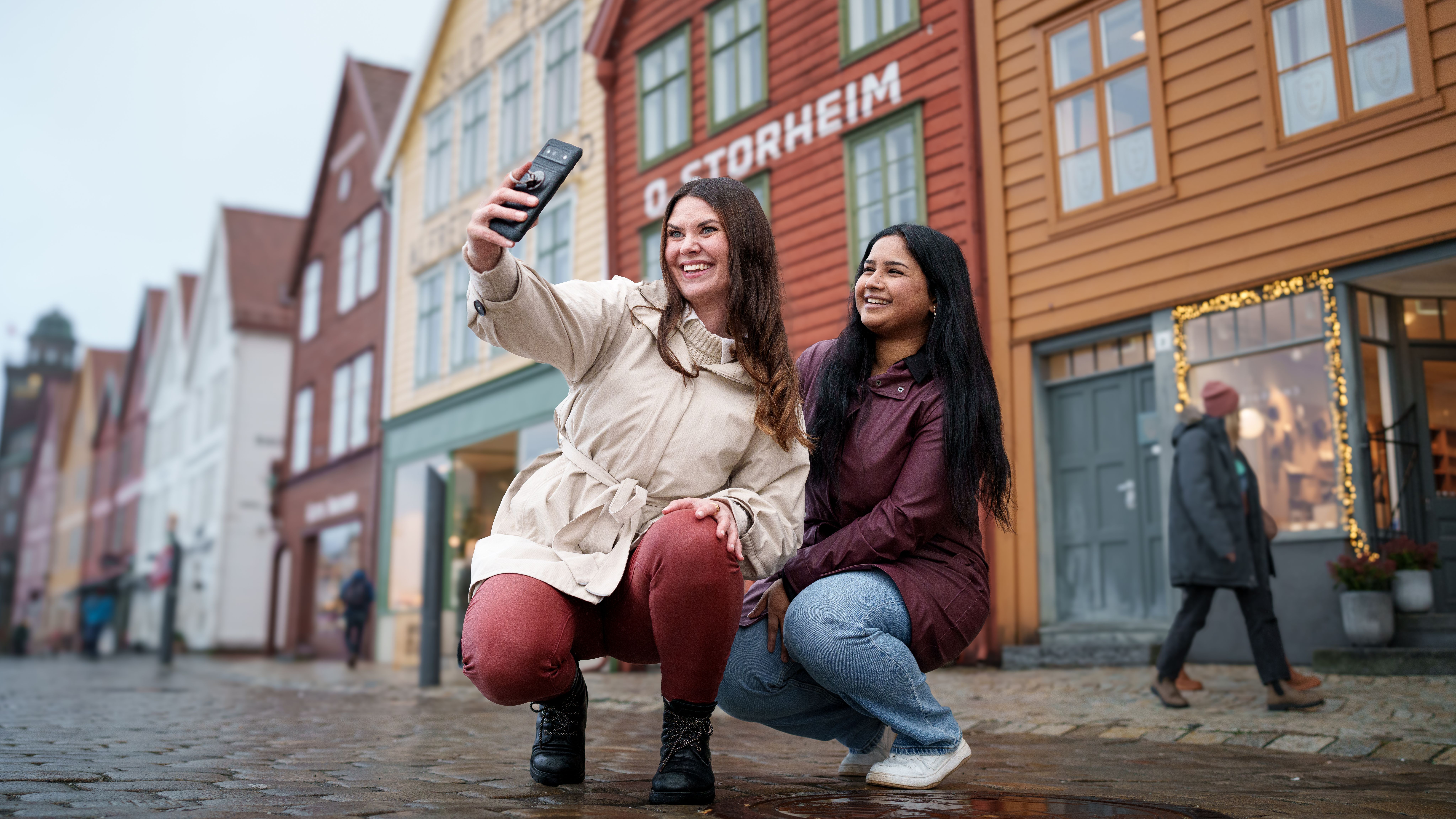 Two women taking a selfie at Bryggen in Bergen, Western Norway