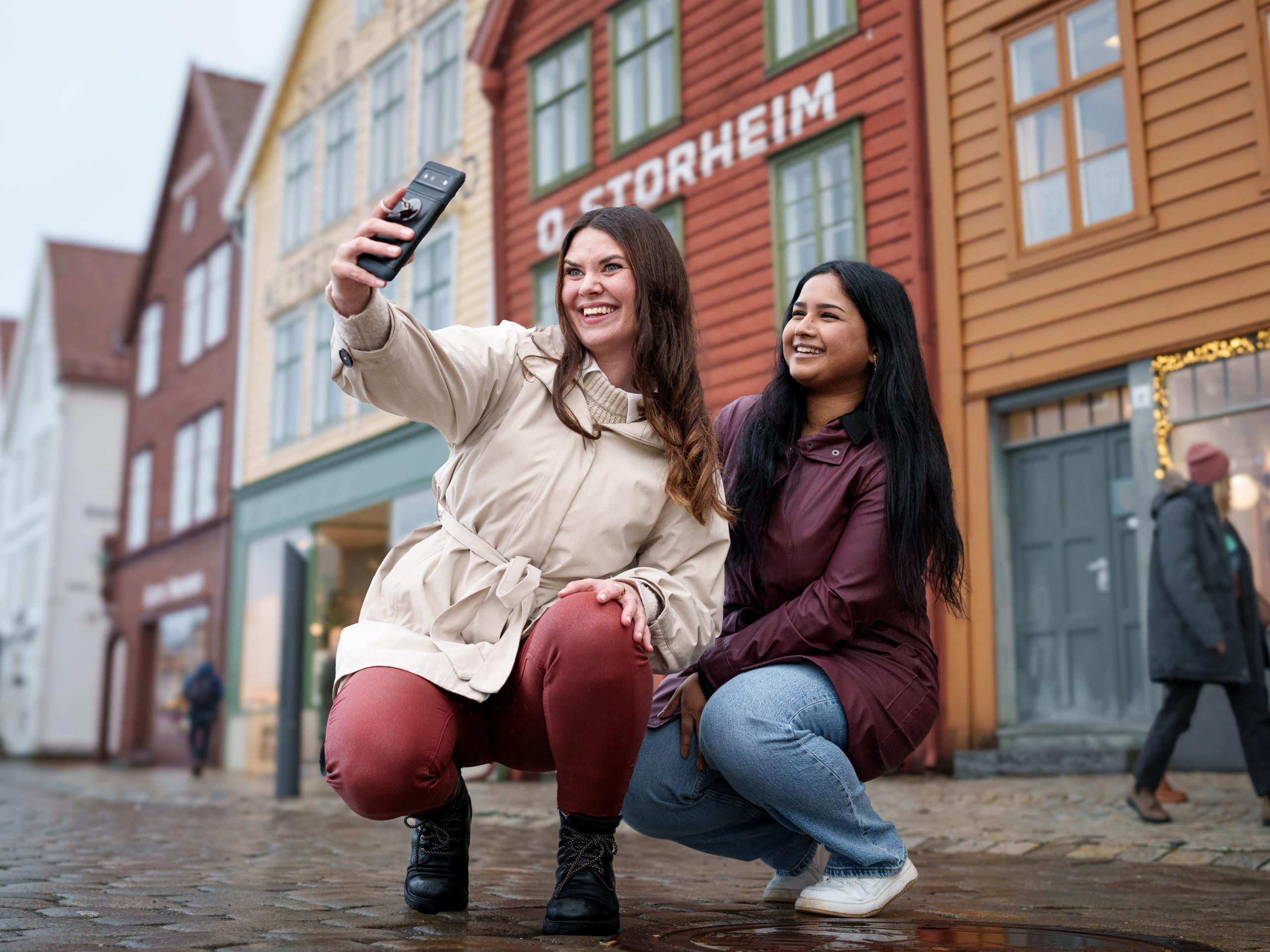 Two women taking a selfie at Bryggen in Bergen, Western Norway