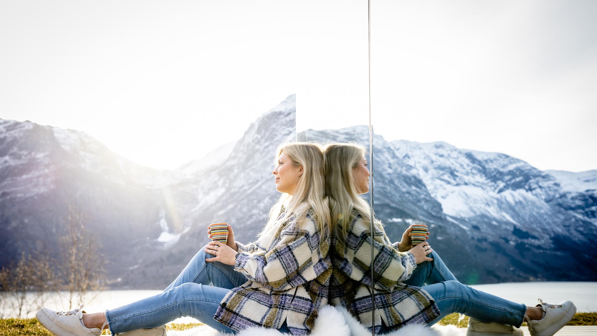 A woman sitting in front of the The Fjord Mirror in Nes Gard in Luster