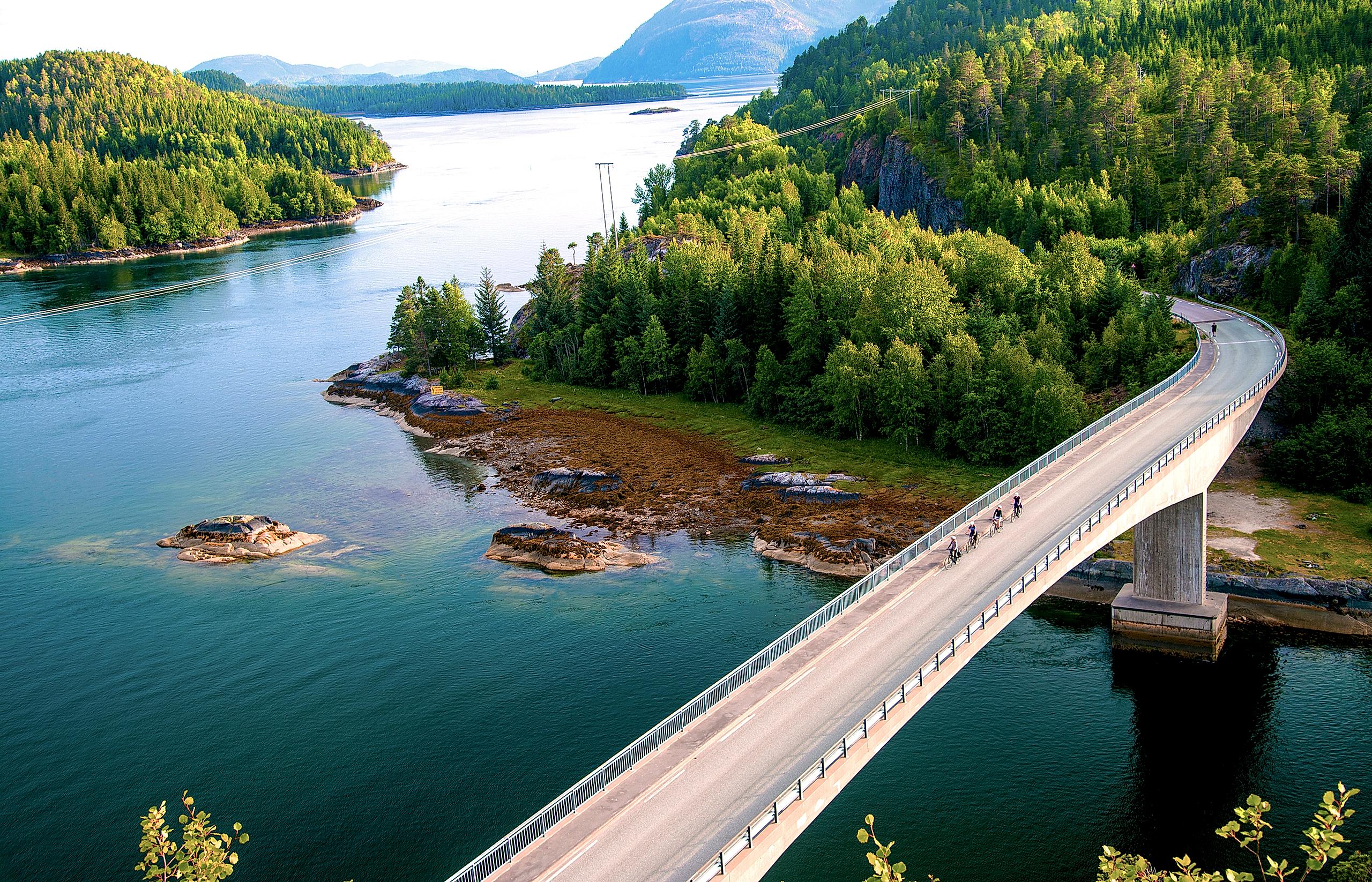 Menschen, die an einem sonnigen Sommertag über eine Brücke an der Küste von Namdalskysten in Trøndelag radeln