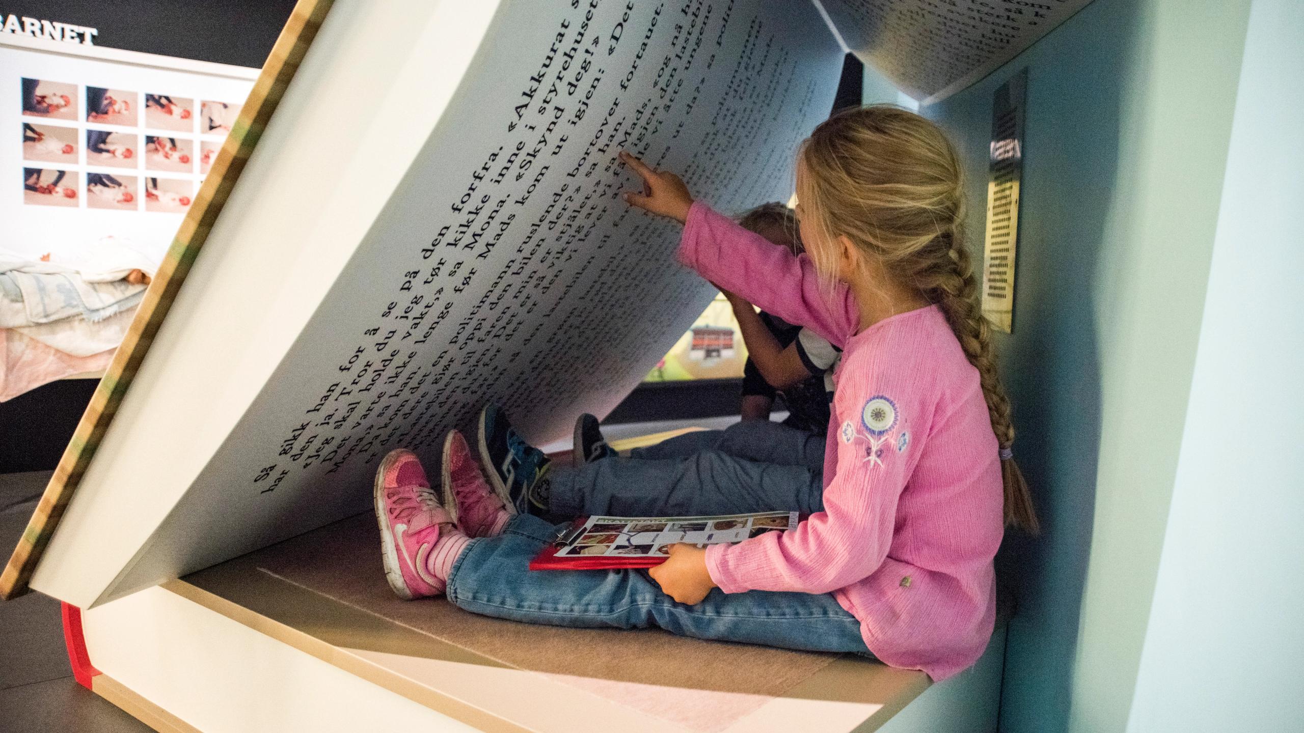 Et barn klatrer rundt i en stor bok på Kuben museum i Arendal på Sørlandet.
