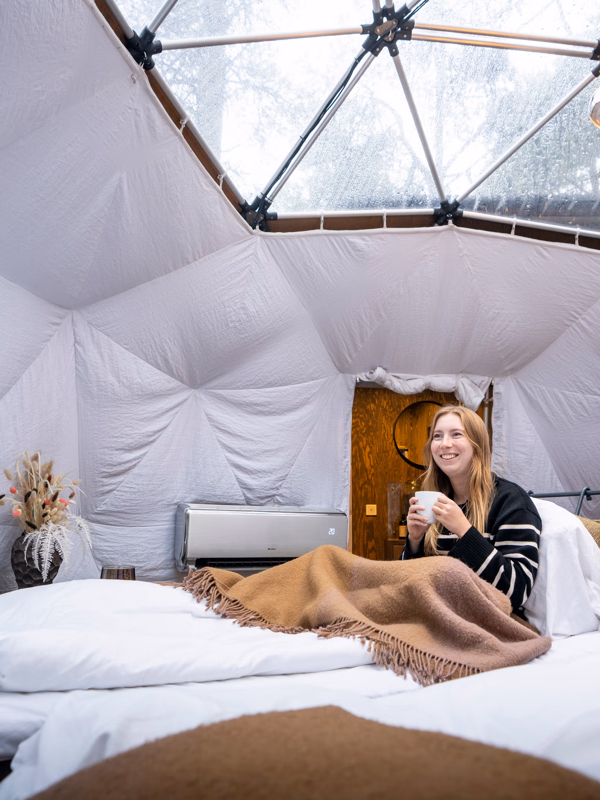 A woman enjoying the view from a Glød Aurora Canvas Dome in Alta