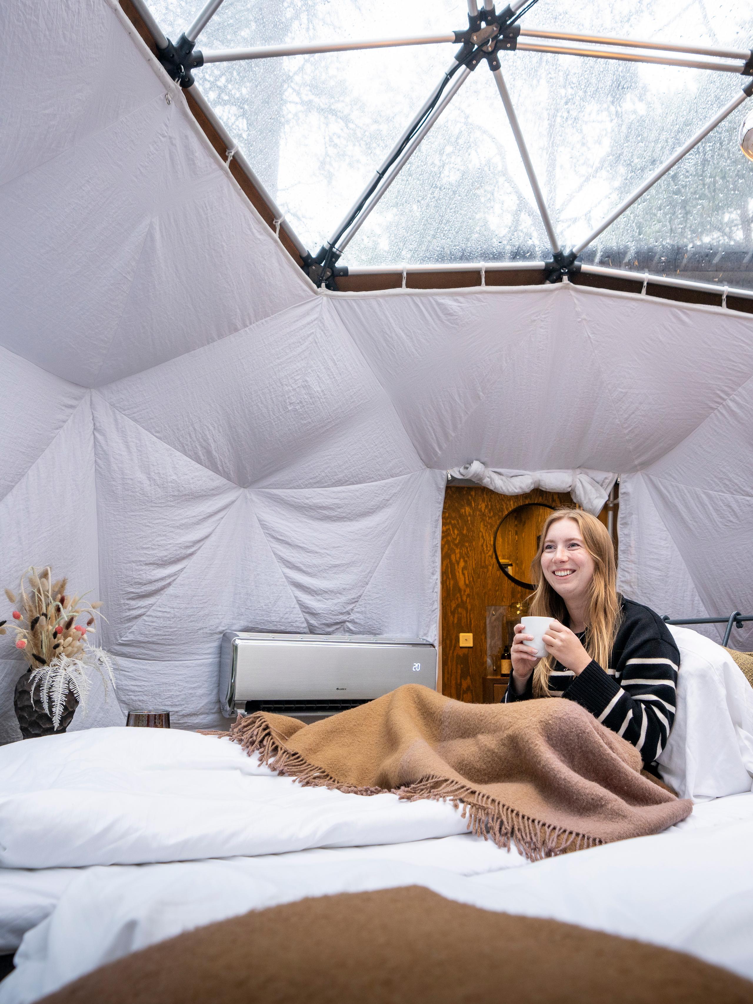 A woman enjoying the view from a Glød Aurora Canvas Dome in Alta