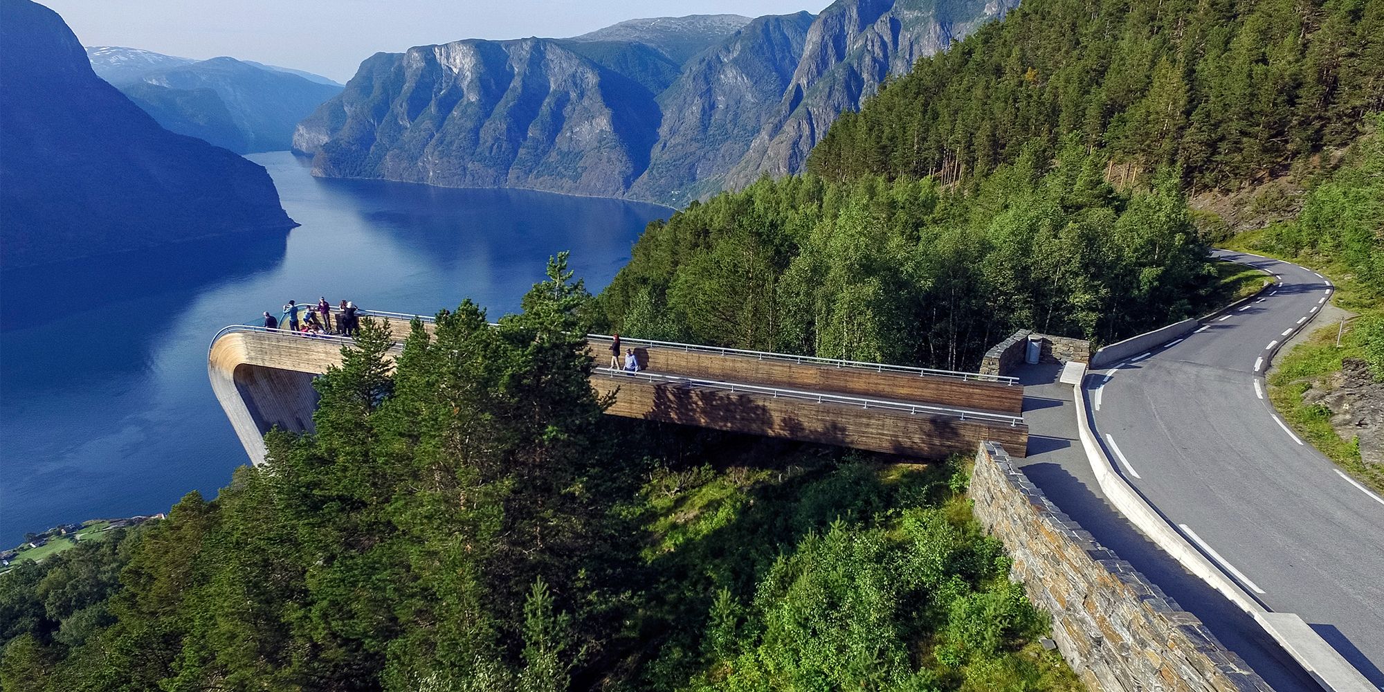 Folk står på Stegastein utsiktsplattform over Aurlandsfjorden ved Nasjonal turistveg Aurlandsfjellet på Vestlandet