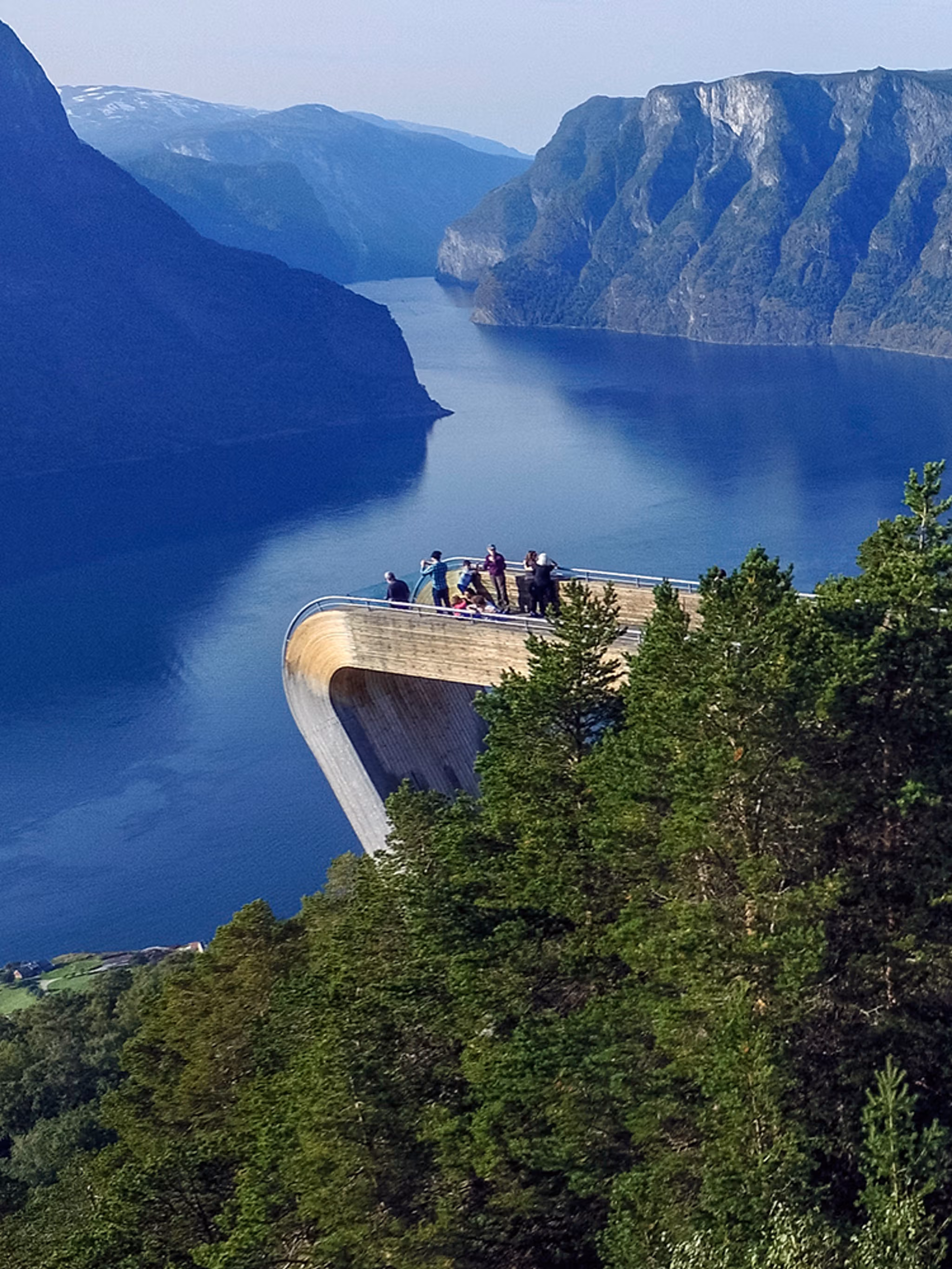 Folk står på Stegastein utsiktsplattform over Aurlandsfjorden ved Nasjonal turistveg Aurlandsfjellet på Vestlandet