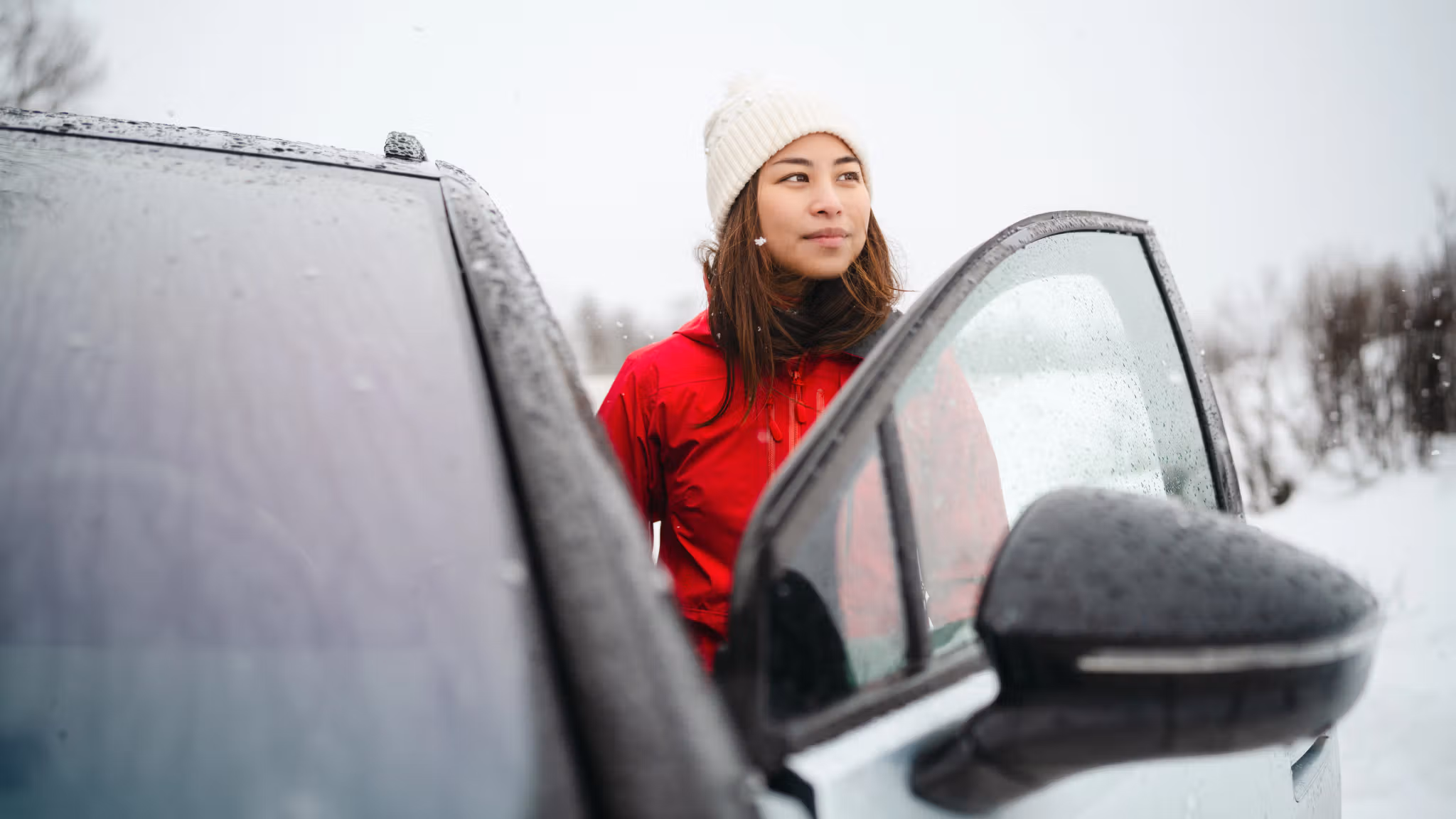 A woman stepping into a car in winter landscape in Norway.