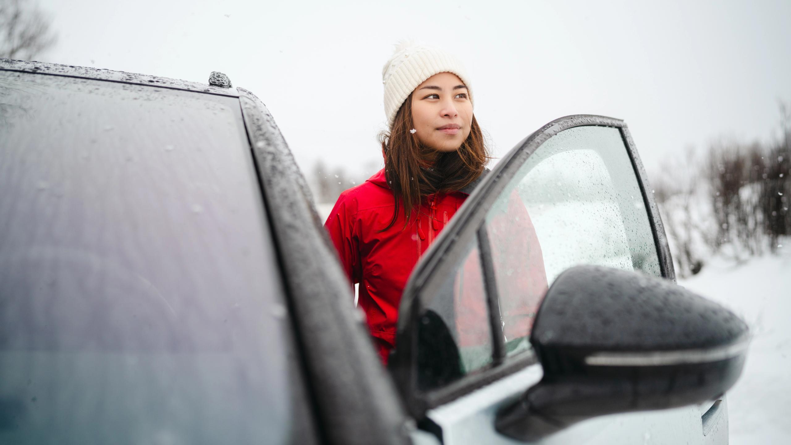 A woman stepping into a car in winter landscape in Norway.