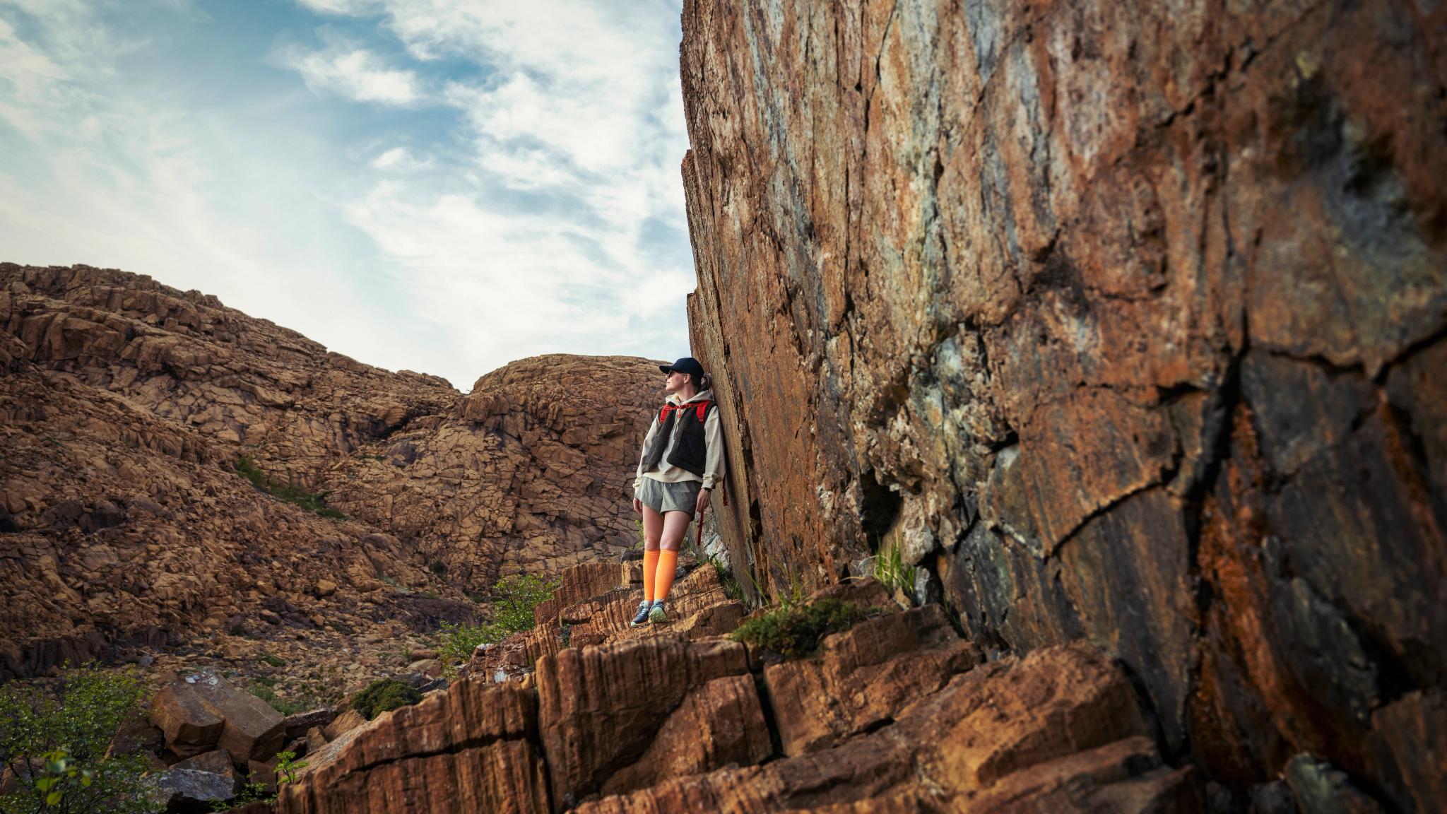 Woman hiking between the red rocks at Leka island in Trøndelag