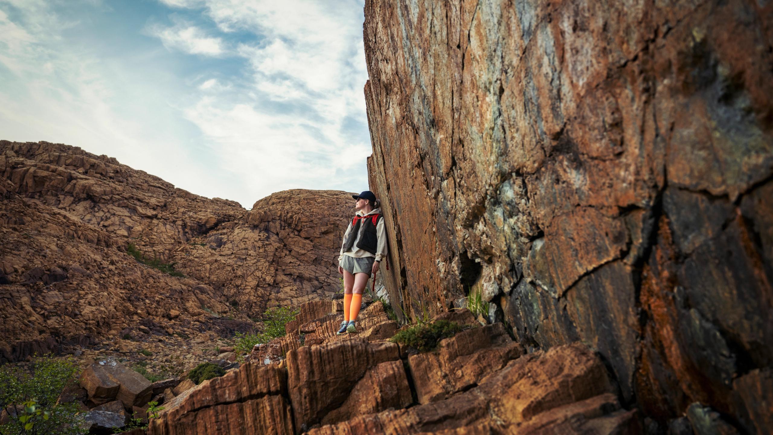 Woman hiking between the red rocks at Leka island in Trøndelag