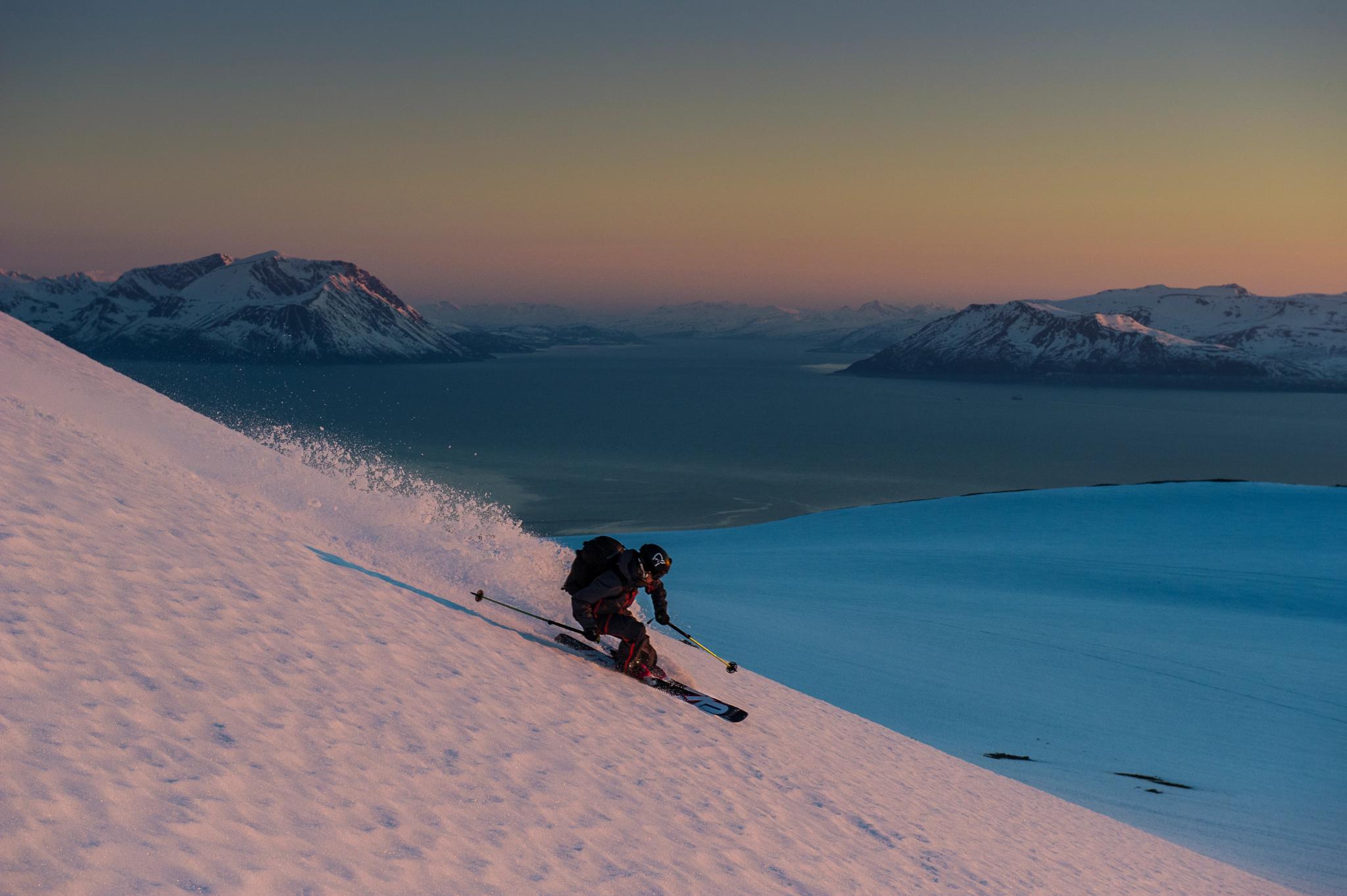 A person skiing down a mountain in Lyngen in sunset.
