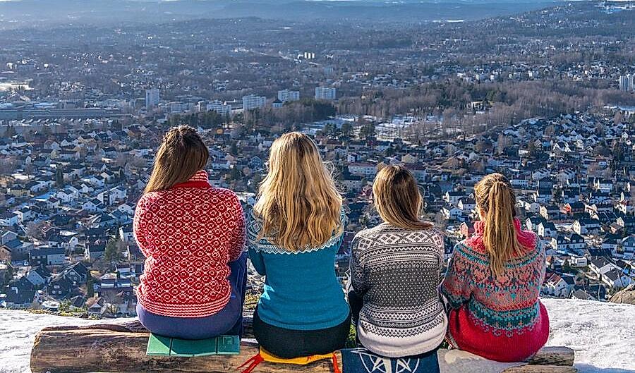 Women sit and watch the view of Oslo in knitted overalls, Norway.