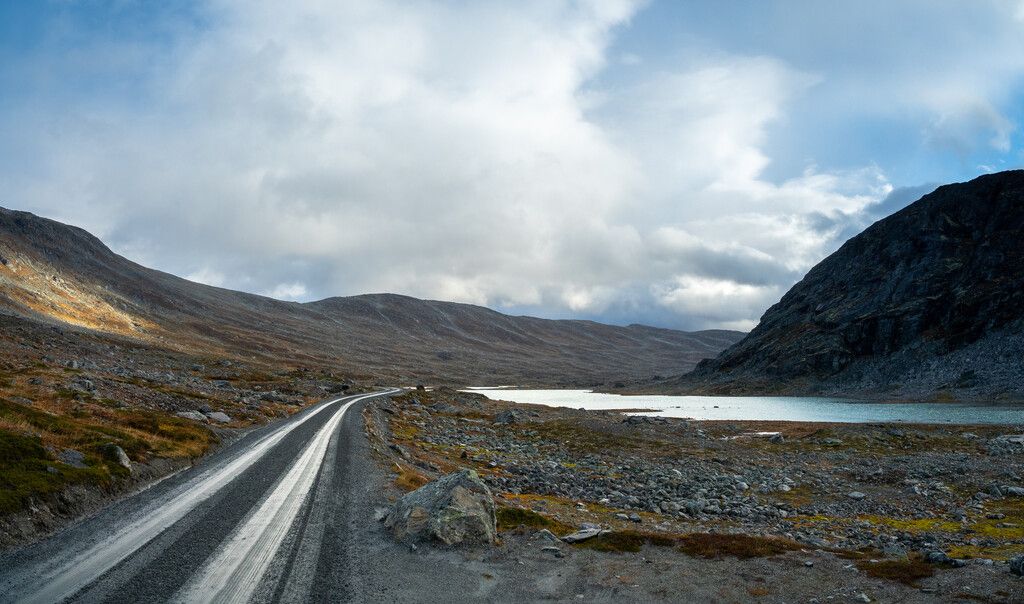 A road high up in the mountains next to a lake.