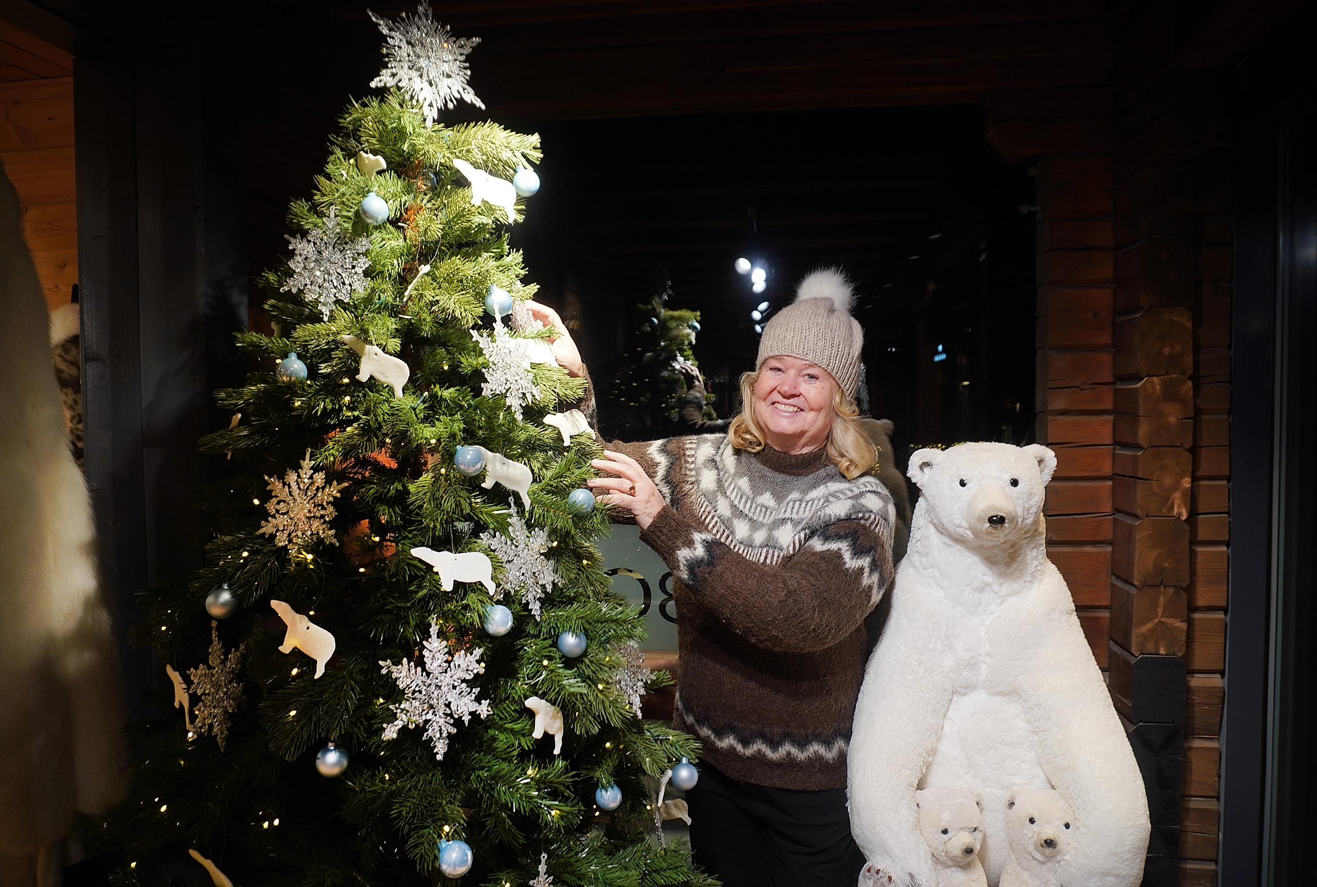 En dame ved siden av en utstoppet isbjørn og et juletre