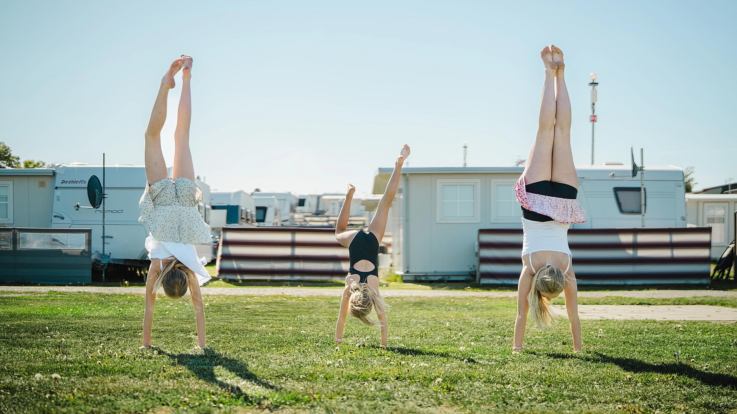 Three girls doing handstands at a campsite