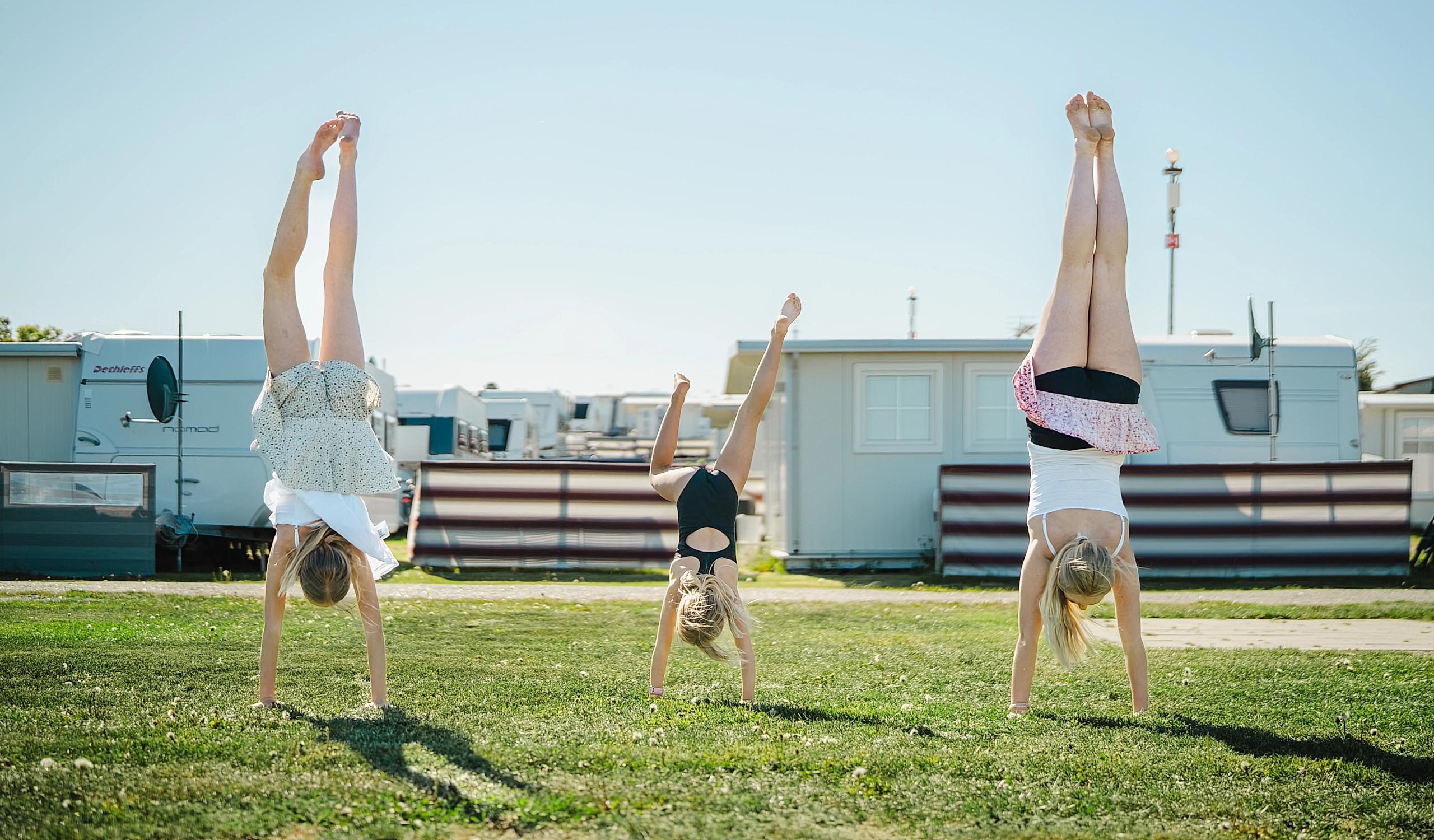 Three girls doing handstands at a campsite