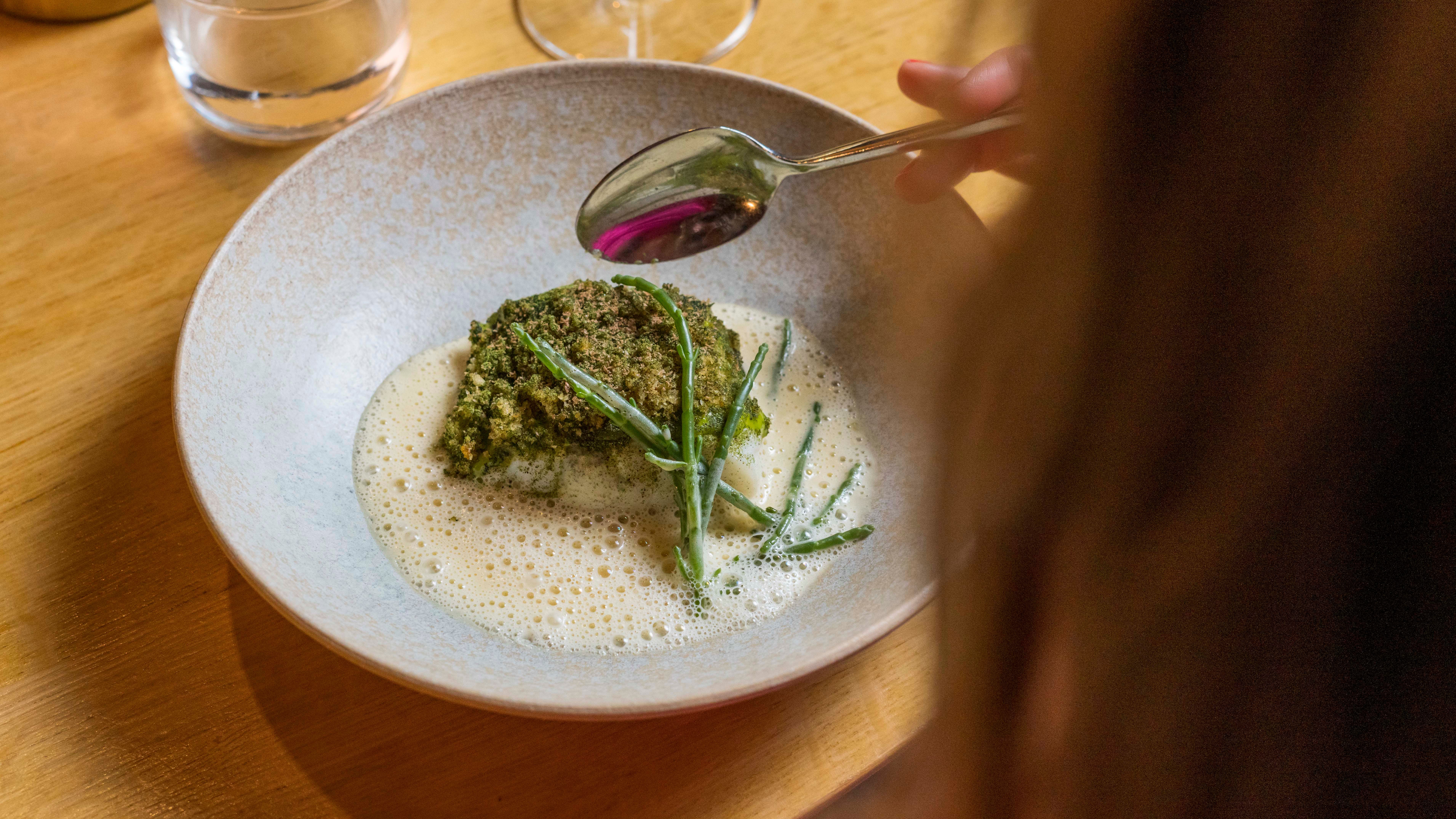 Woman with a plate of cod from Borgundfjord at Bro restaurant in Ålesund