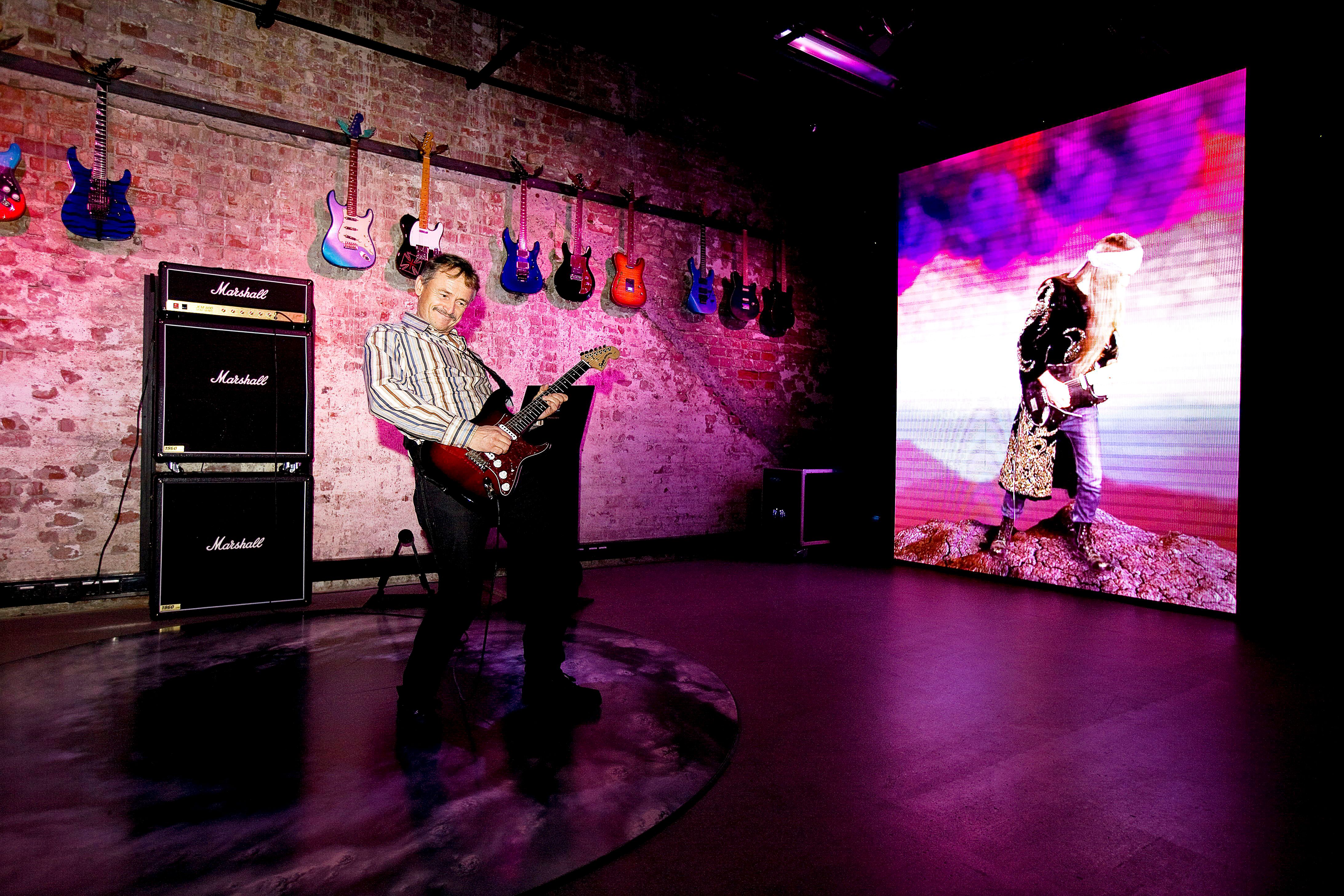 A man playing a guitar at the Rockheim museum in Trondheim, Norway