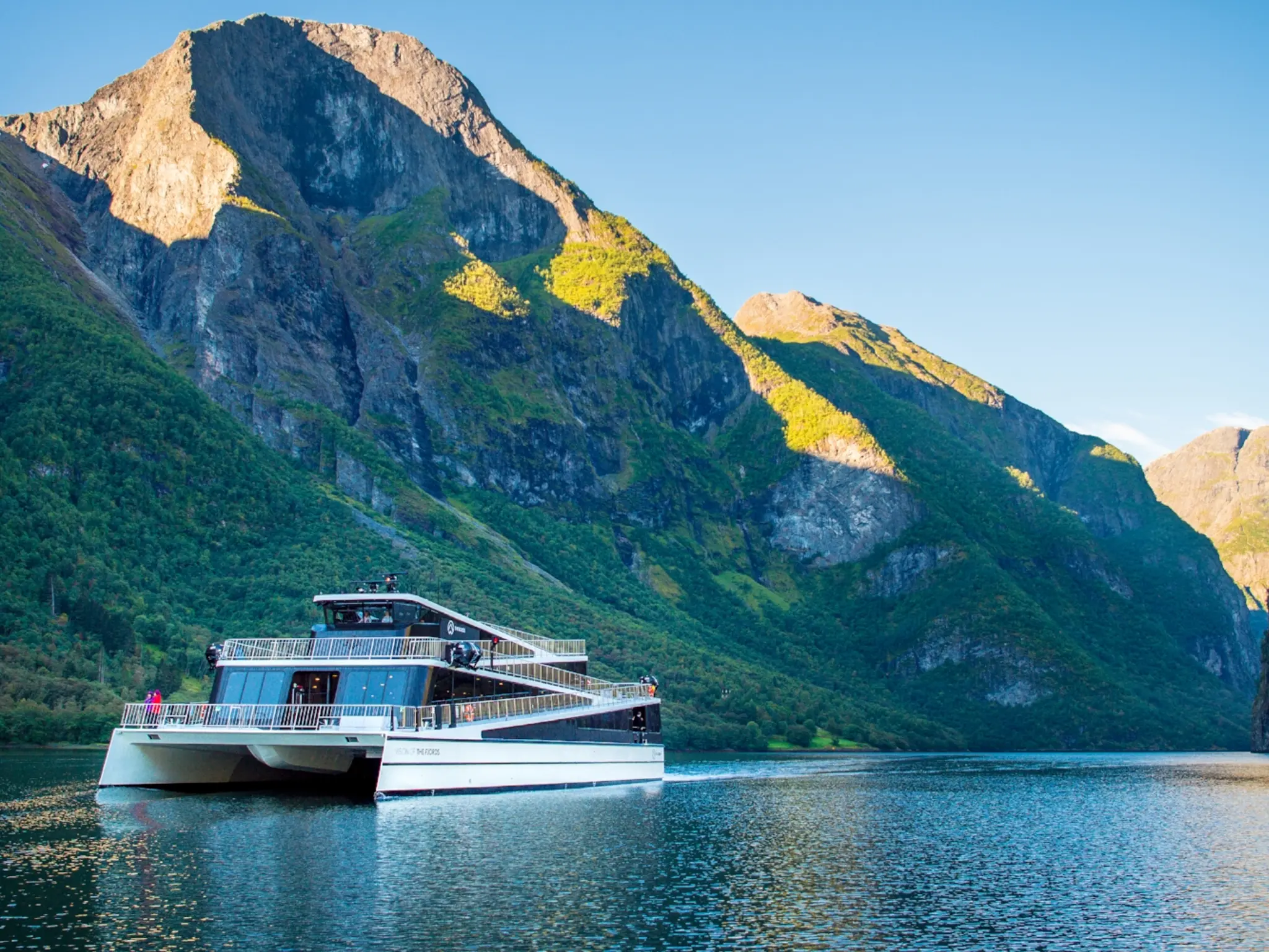 The hybrid electric vessel Vision of the Fjords cruising the Aurlandsfjorden fjord surrounded by mountains