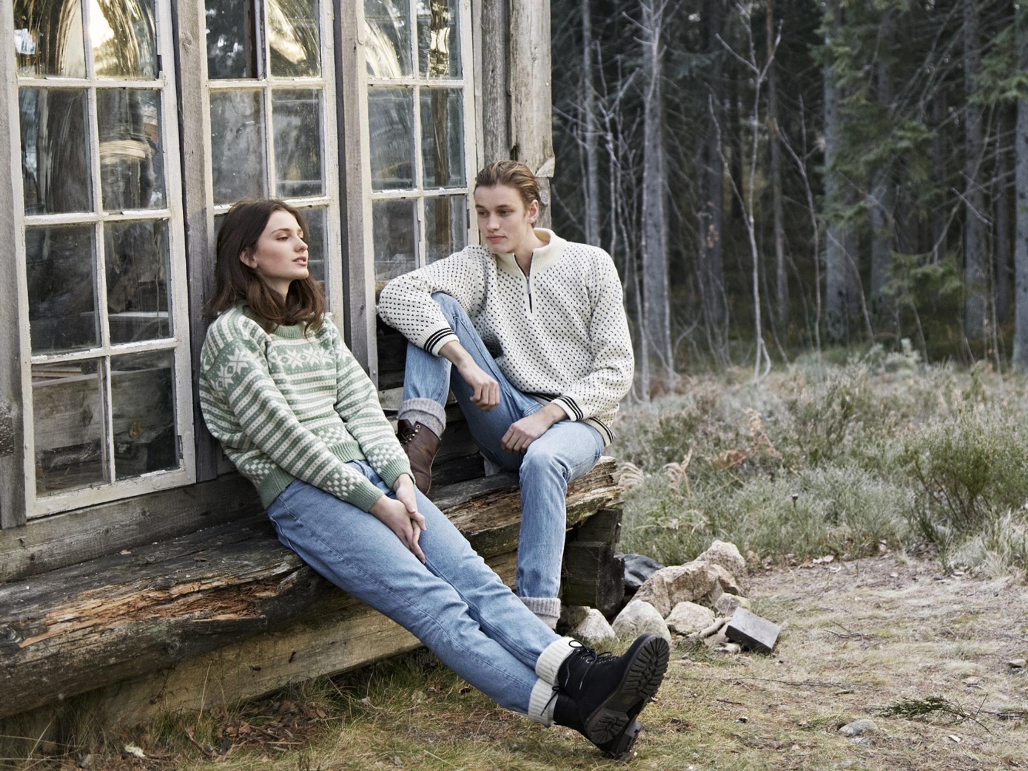 Two girls sitting on a bench outside, wearing woollen pullovers