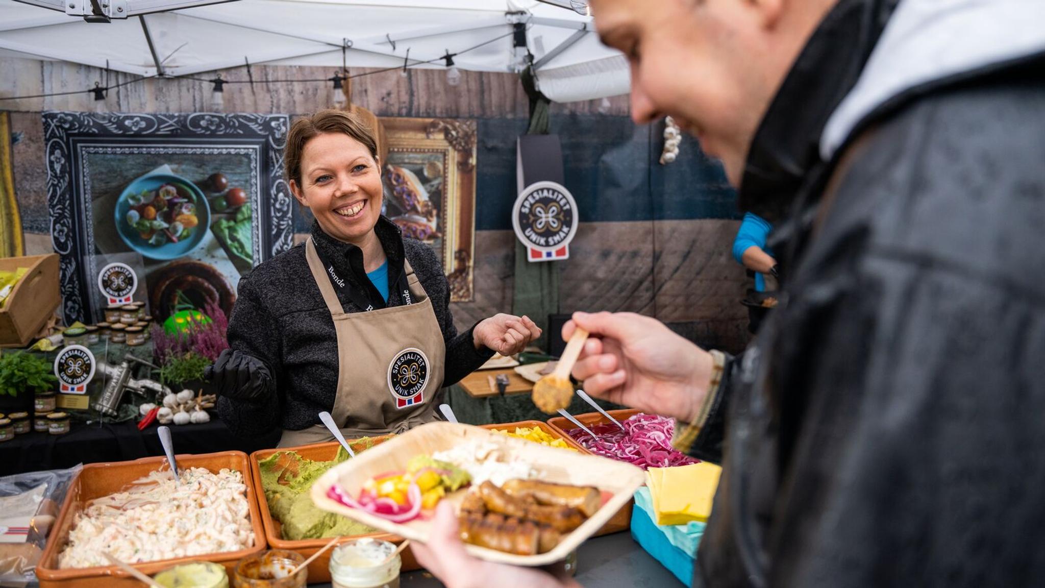 En mann spiser en servering med forskjellige pølser på Matstreif matfestival i Oslo