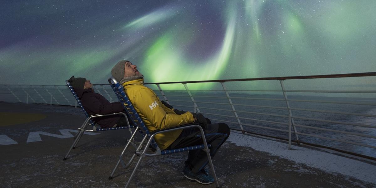 To personer ser på nordlyset fra Hurtigruten