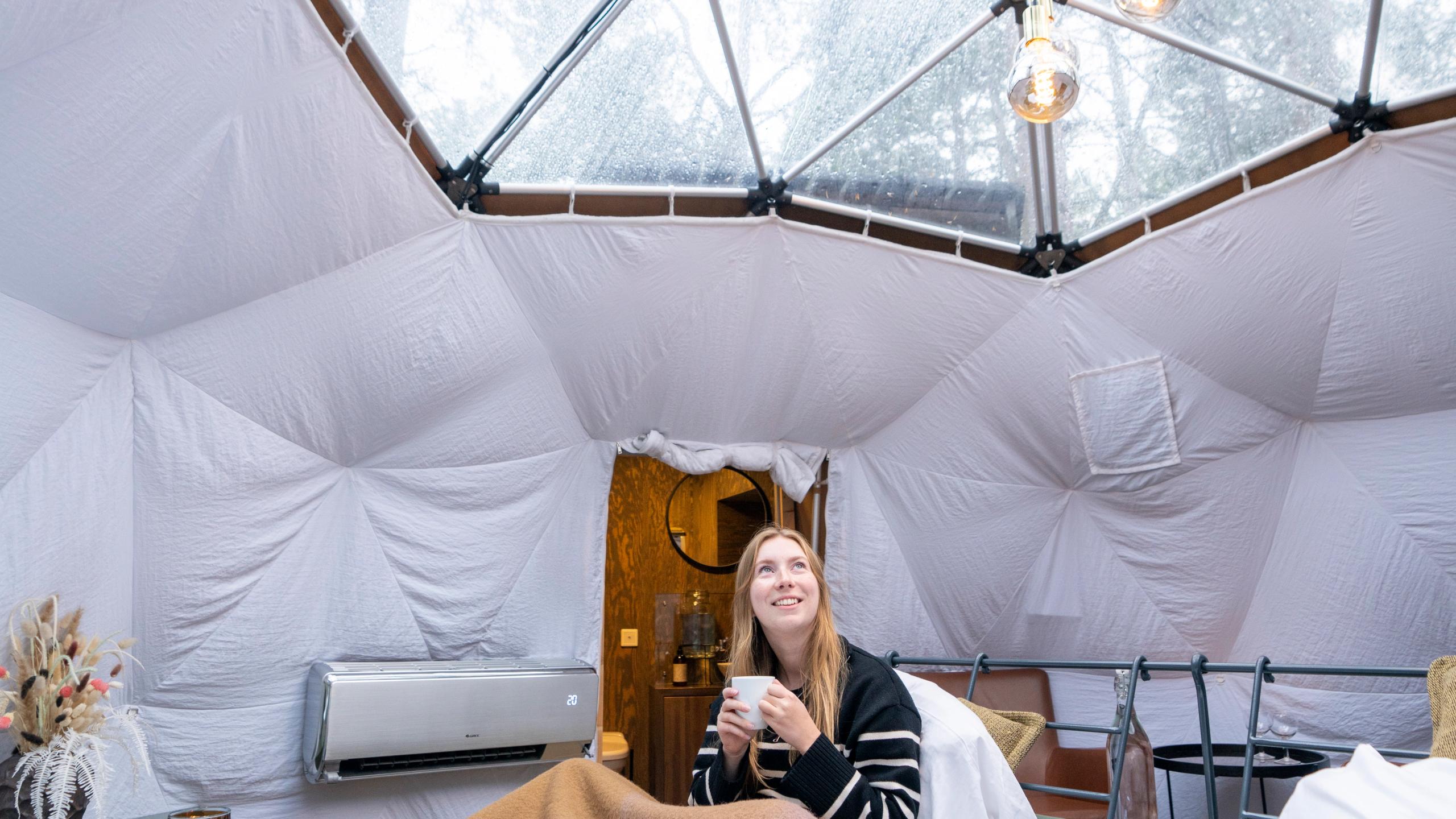 A woman enjoying the view from a Glød Aurora Canvas Dome in Alta