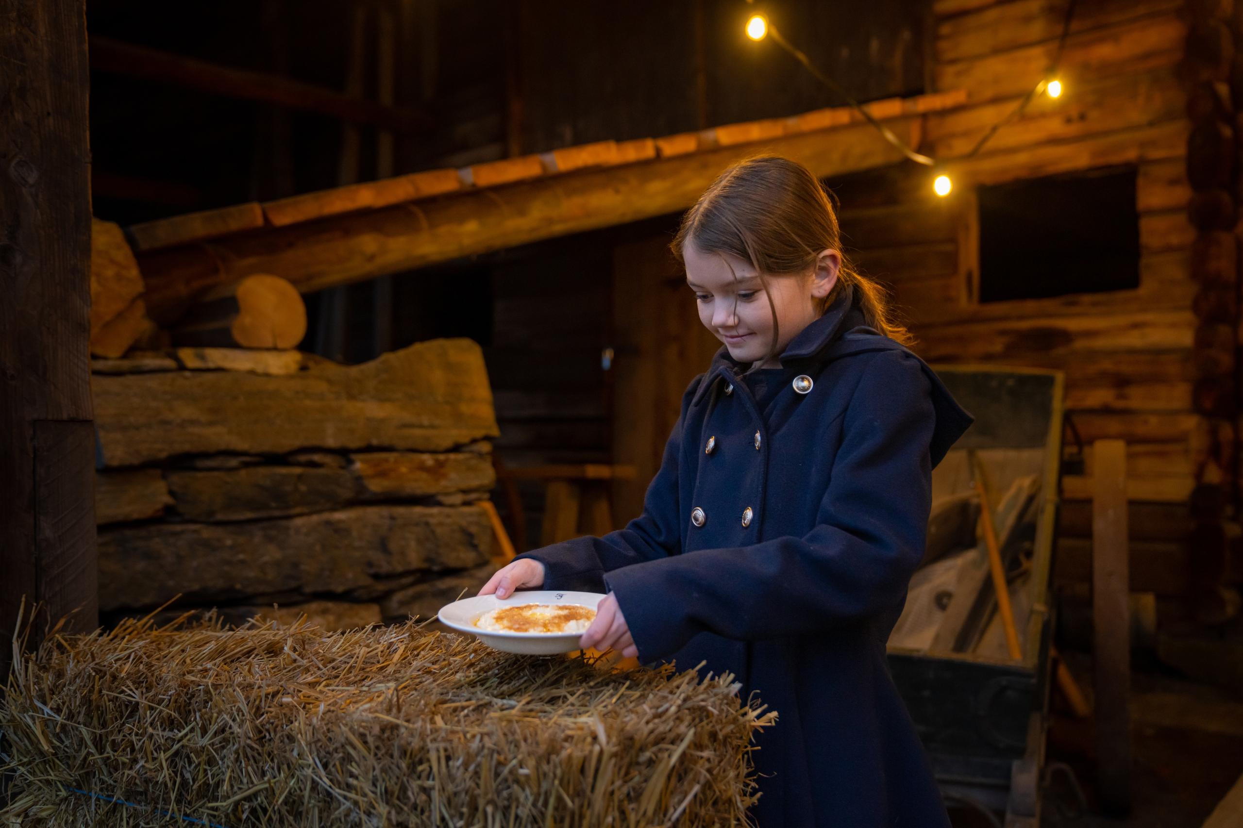 A girl is setting out a bowl of Christmas porridge to Santa at Norsk Folkemuseum in Bygdøy, Eastern Norway