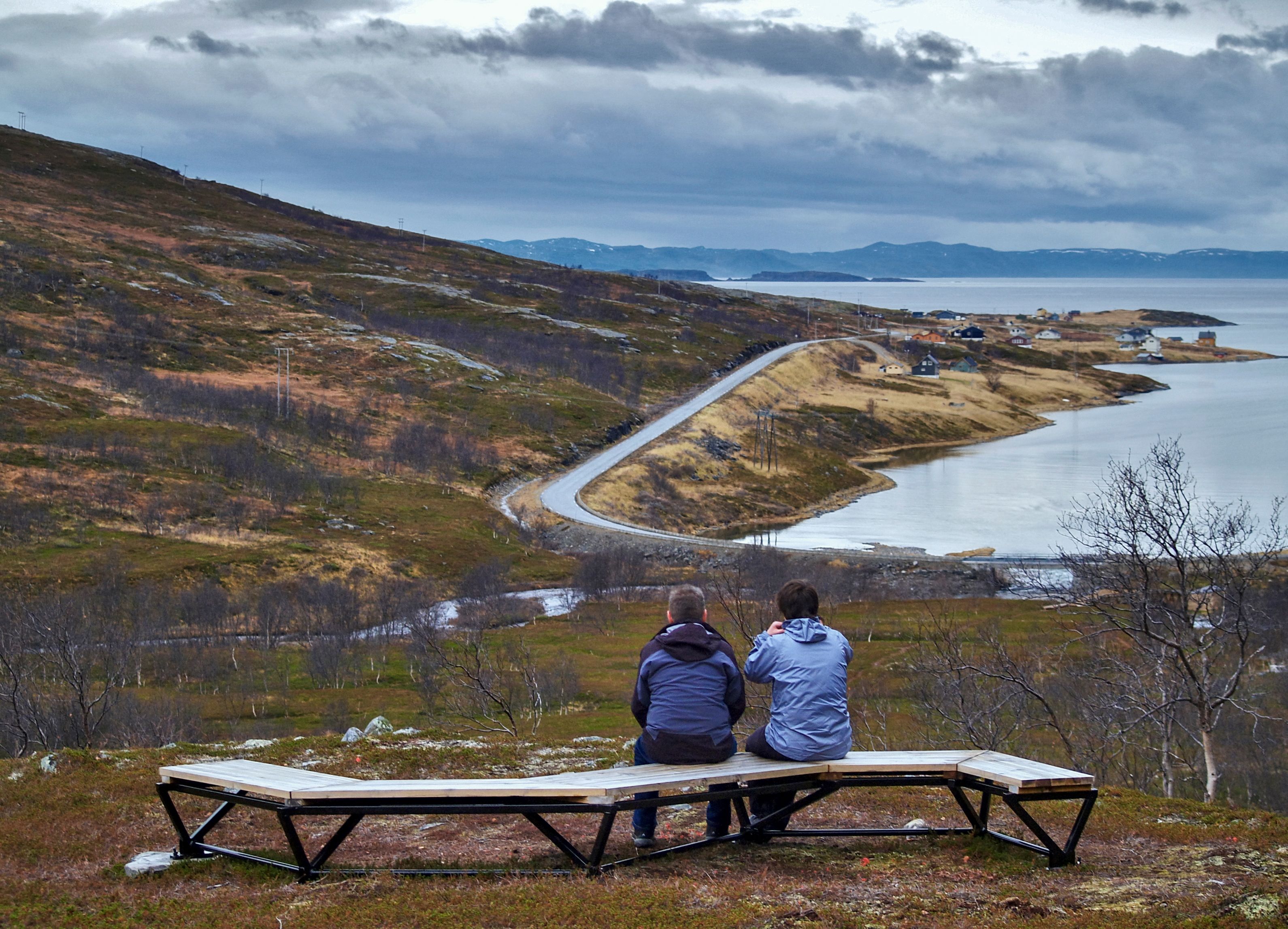 Two persons sitting on a bench at the Lillefjord Rest Area 