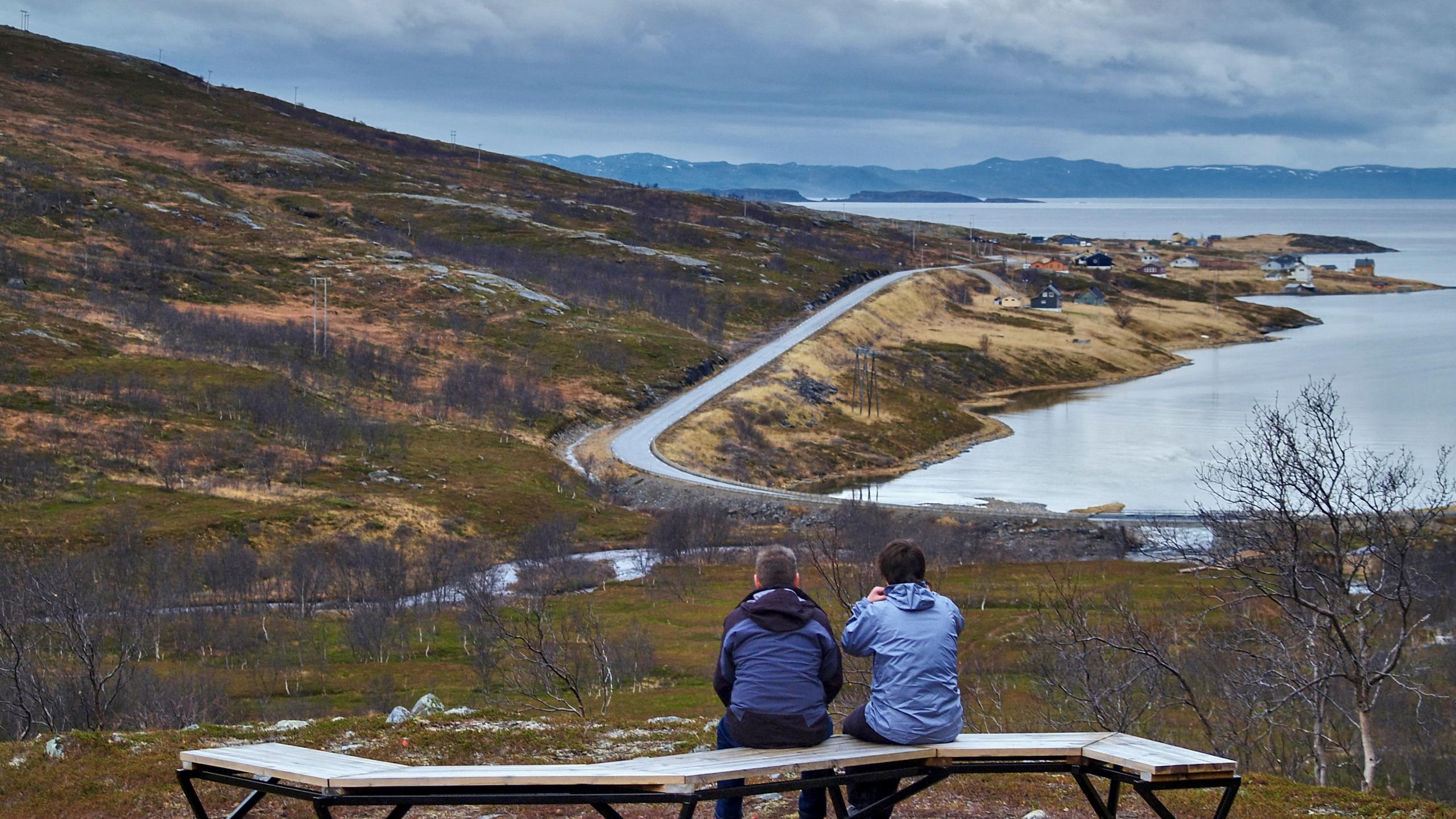 Two persons sitting on a bench at the Lillefjord Rest Area