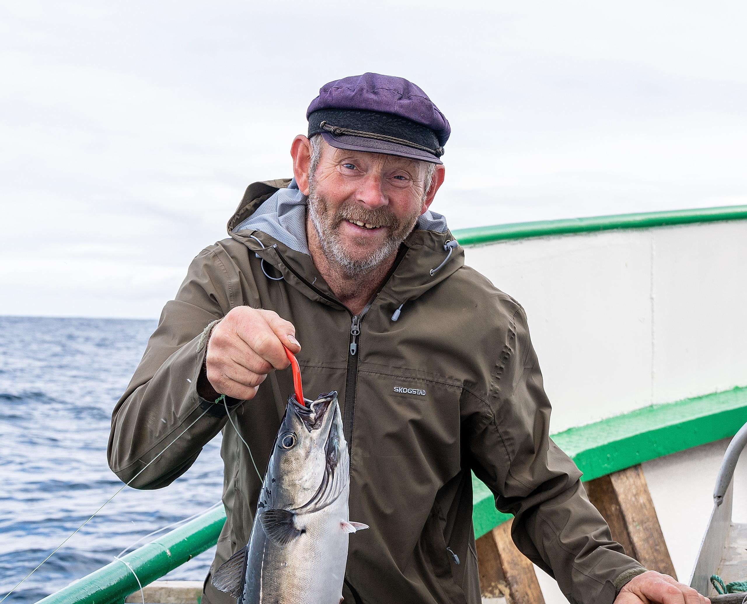 En mann holder en fisk han akkurat har fanget.
