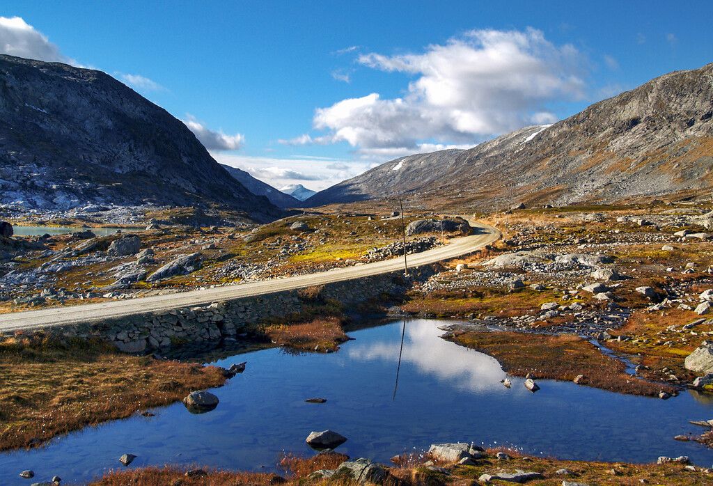 A road high up in the mountains next to a lake.