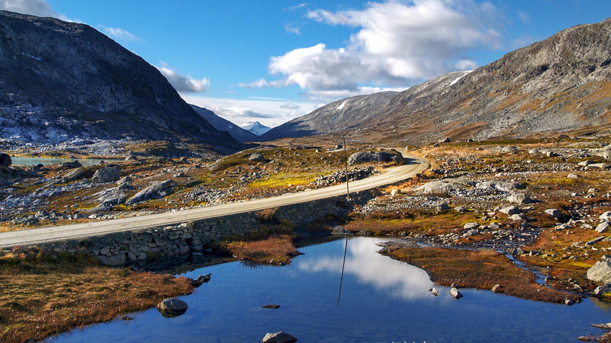A road high up in the mountains next to a lake.