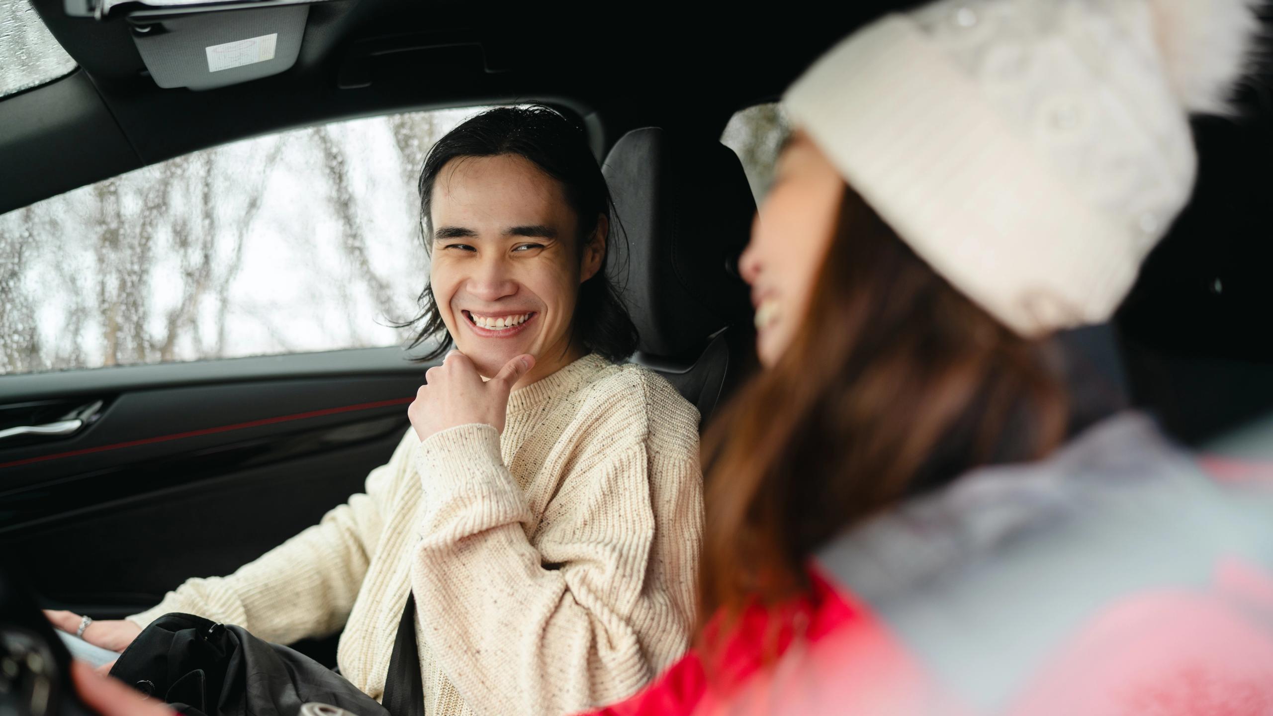 A man and a woman sitting inside a car in winter landscape in Northern Norway.