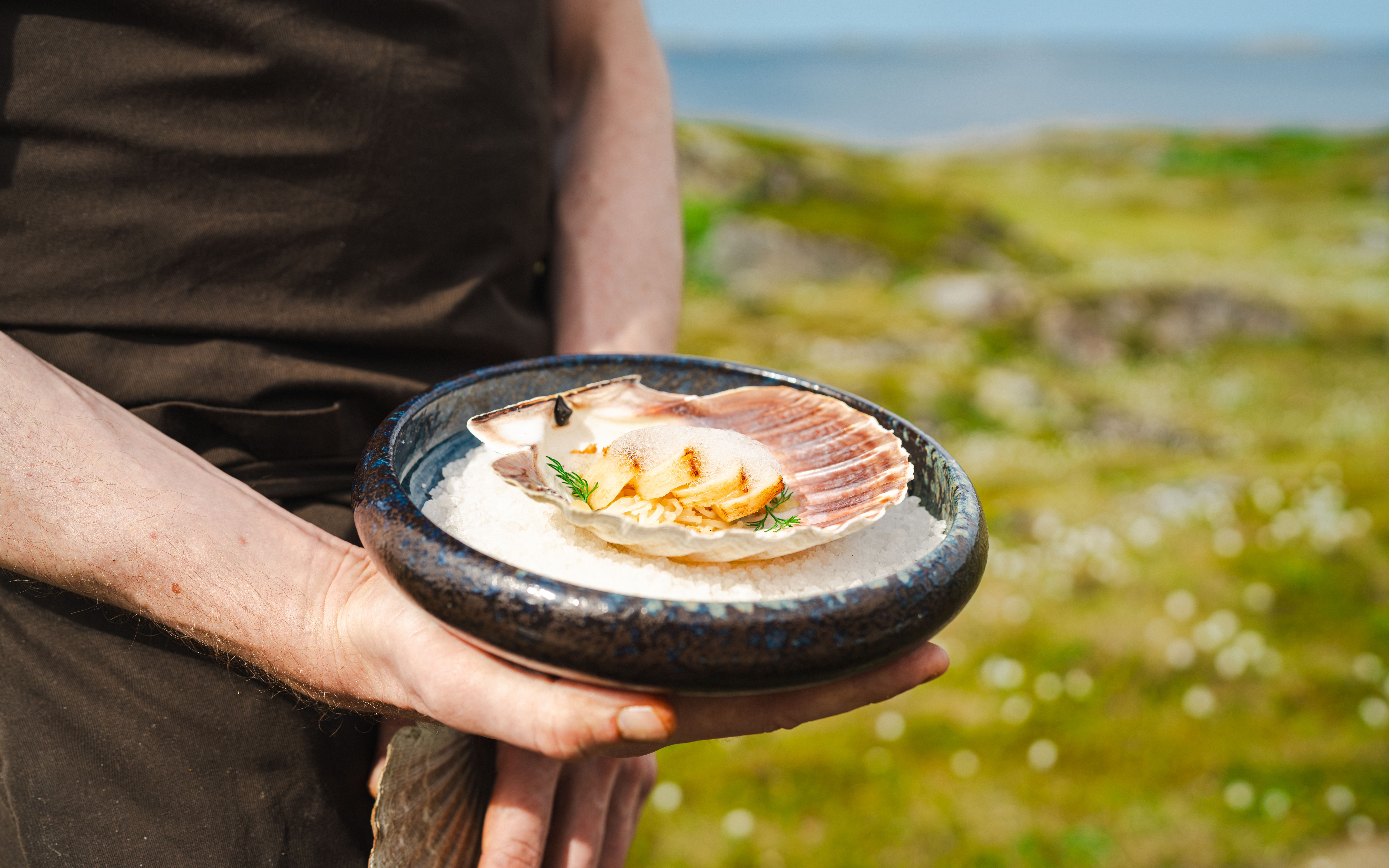 A hand holding a plate of seafood