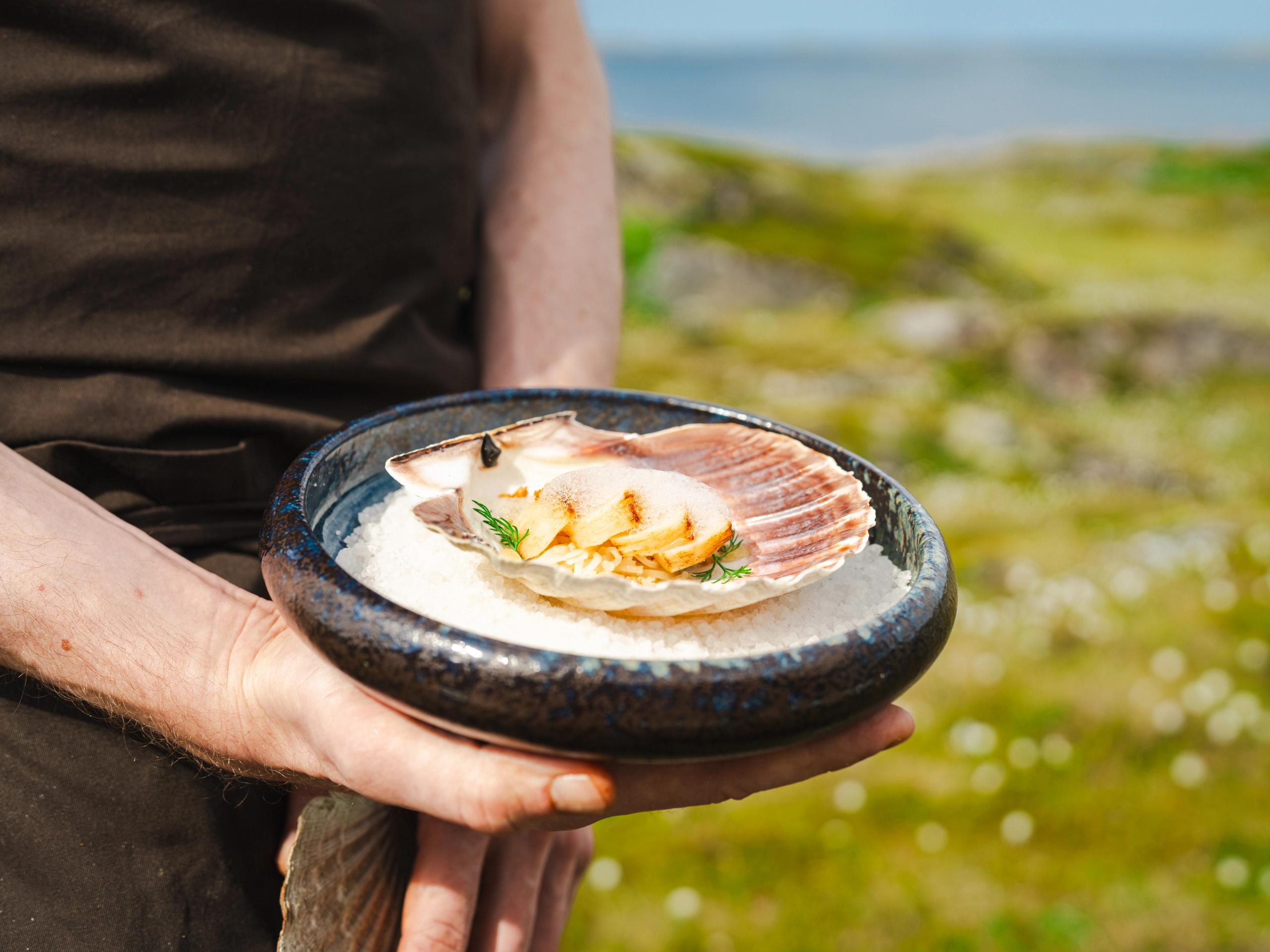 A hand holding a plate of seafood