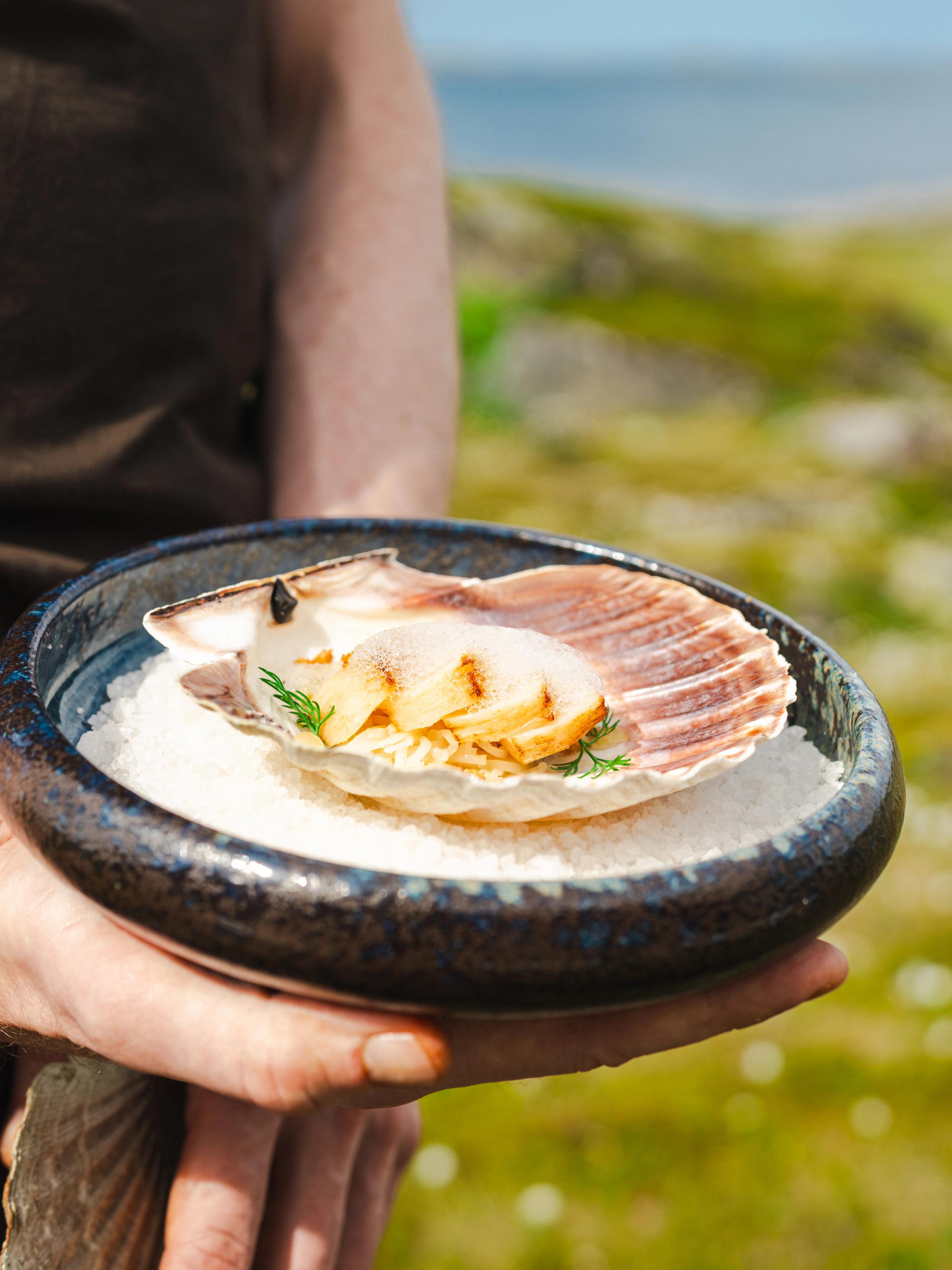 A hand holding a plate of seafood