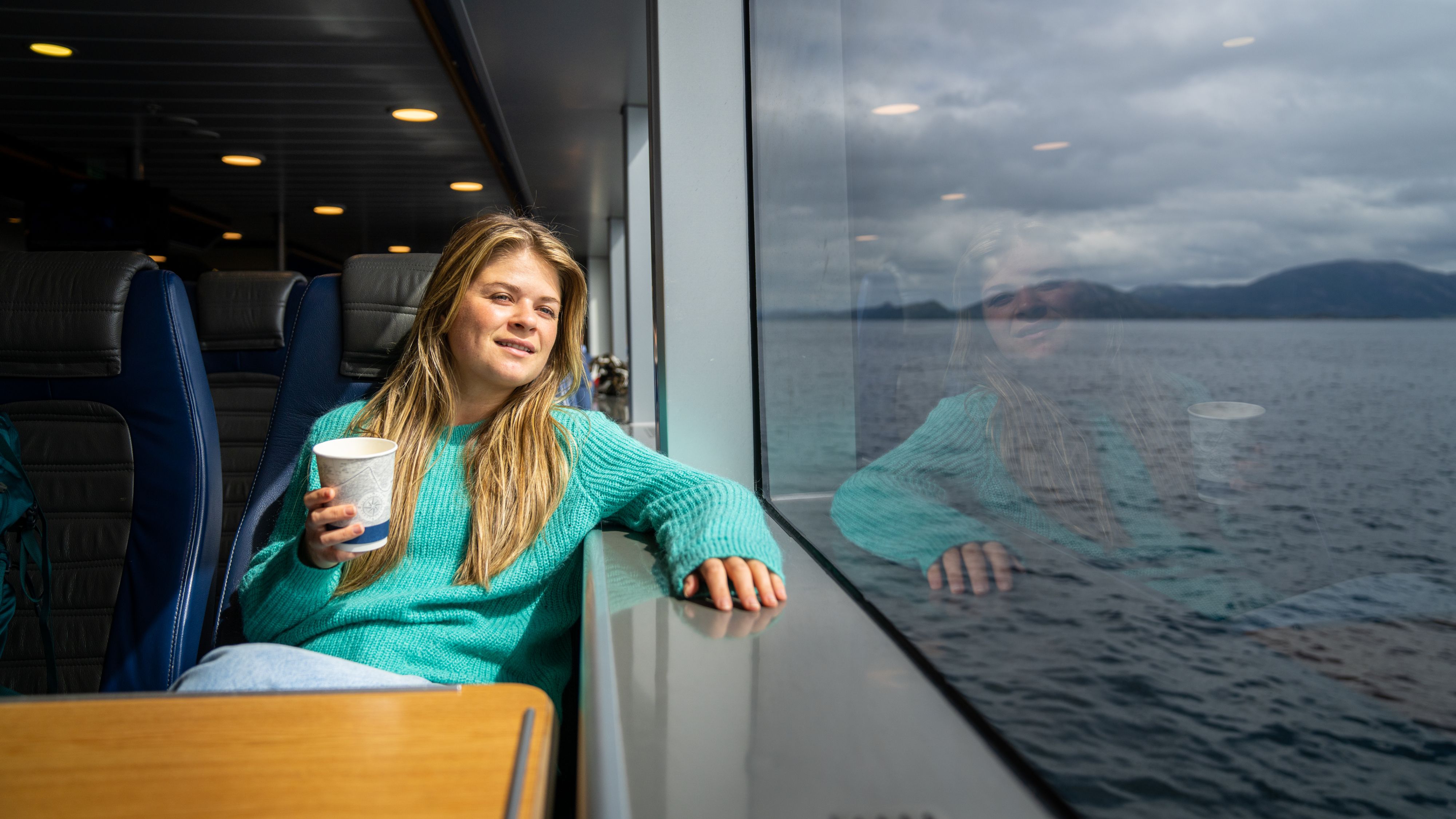 A woman looking out the window from the express boat at sea