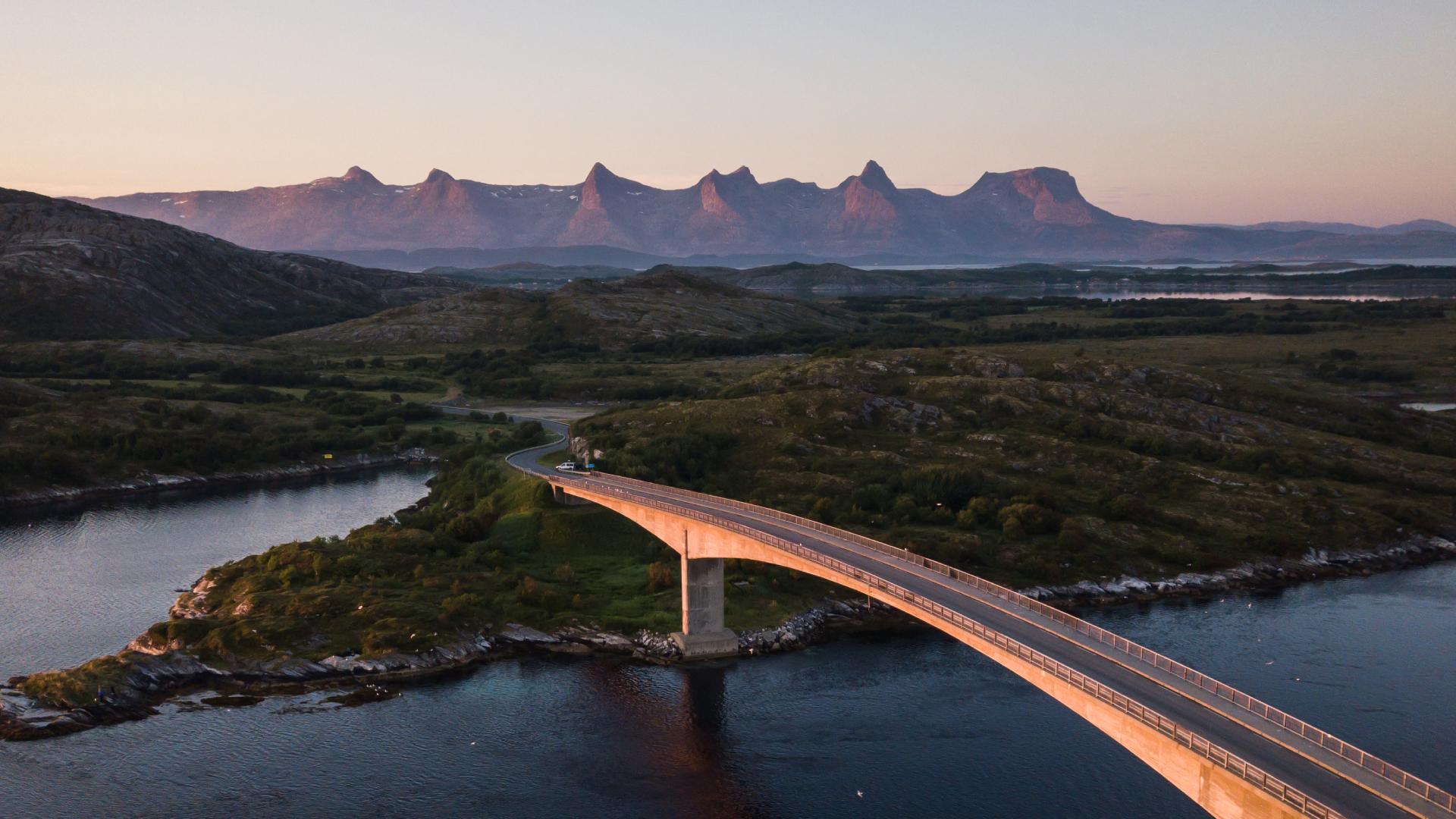 En bro som knytter Herøy til en annen øy på Helgeland. I bakgrunnen er fjellformasjonen De syv søstre