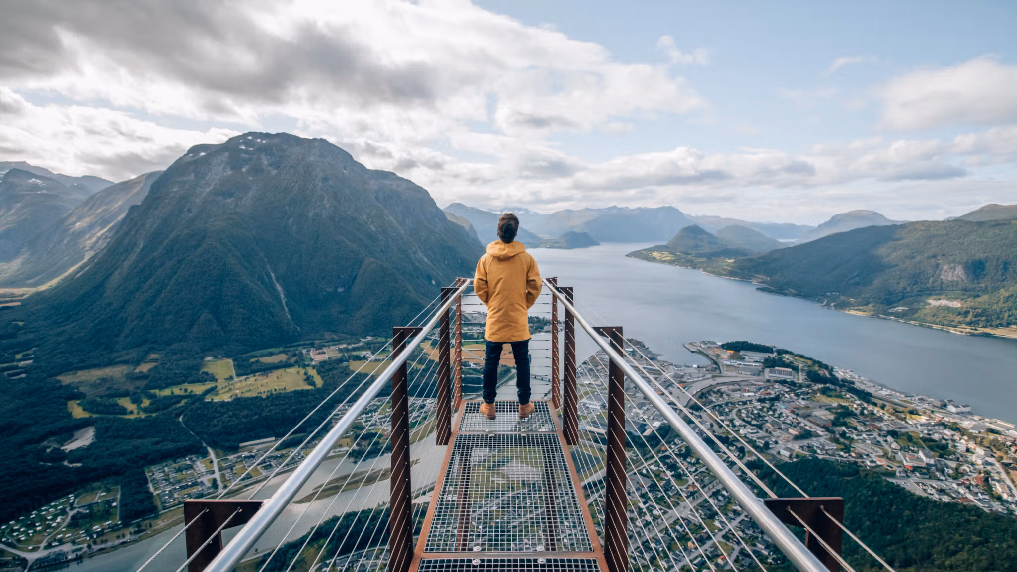 Una persona sulla punta della piattaforma panoramica Rampestreken osserva il fiordo e le montagne di Åndalsnes nel Nordovest dei fiordi, Norvegia dei fiordi