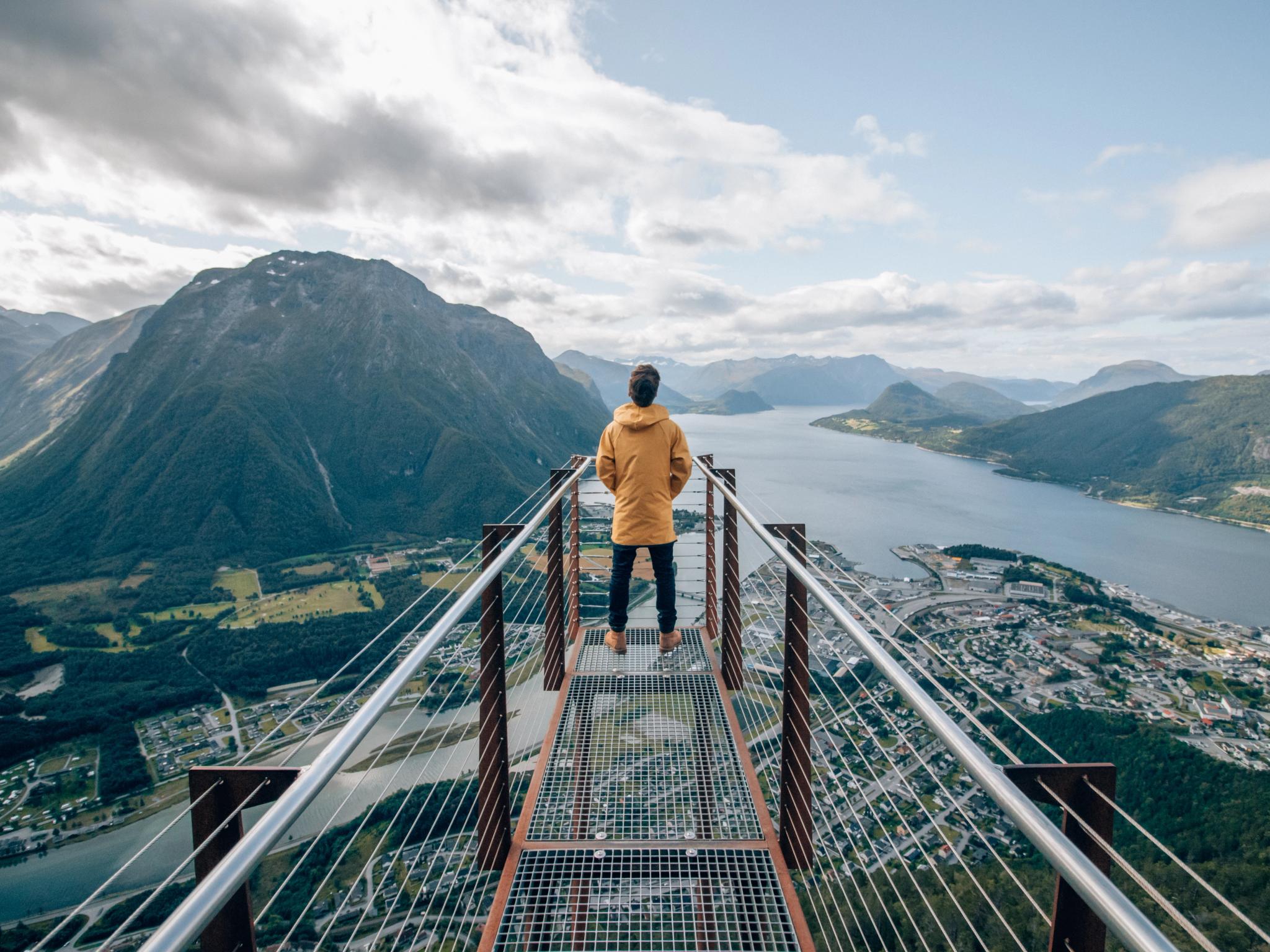 Una persona sulla punta della piattaforma panoramica Rampestreken osserva il fiordo e le montagne di Åndalsnes nel Nordovest dei fiordi, Norvegia dei fiordi
