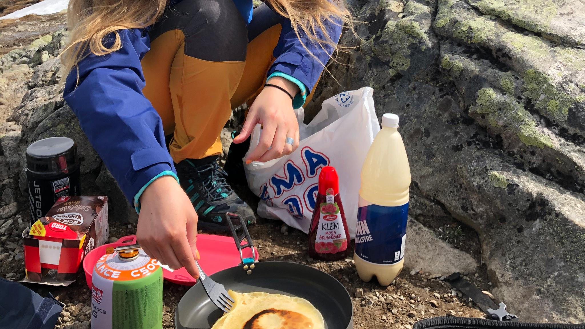 A woman making pancakes outside on the mountain